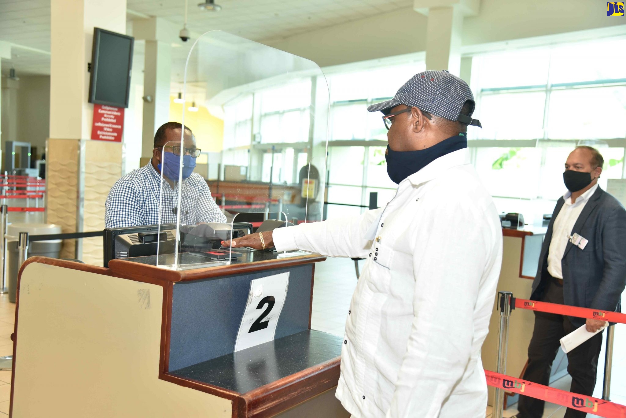 Peter Hall (left), Chief Operations Officer at Sangster International Airport, assists Minister of Tourism, Hon Edmund Bartlett in testing an electronic scanner that passengers passing through the airport will be using to avoid hand-to-hand contact with Immigration Officers at the airport. At right is Chairman of the Tourism Product Development Company, Ian Dear who was one of several key persons accompanying Minister Bartlett on COVID-19 Tourism Recovery Fact Finding Tour in Montego Bay and Ocho Rios on Wednesday, June 3, 2020.