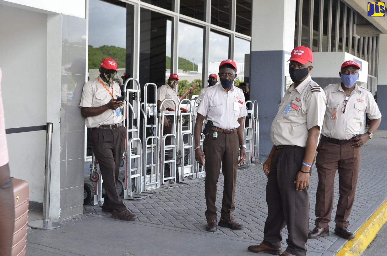 Red Cap porters based at the Sangster International Airport in Montego Bay, St. James, await the arrival of travellers outside the departure lounge as the airport reopened for international travel on Monday (June 15).
