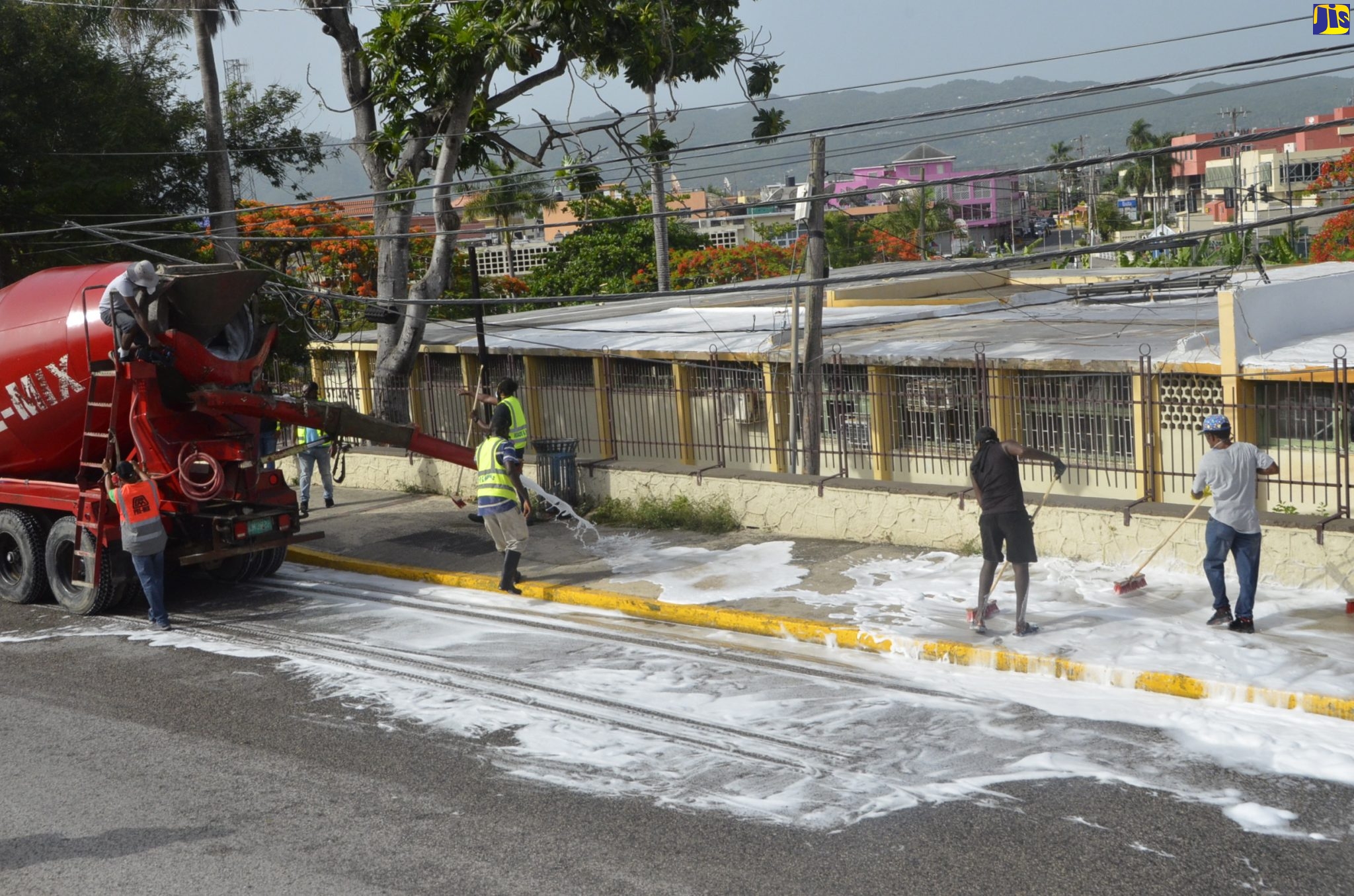 Sanitiser is being ejected from a premix truck on to a sidewalk along St. James Street, while workers from the St. James Municipal Corporation scrub the area. Occasion was a sanitisation exercise in Montego Bay on Sunday (June 28).