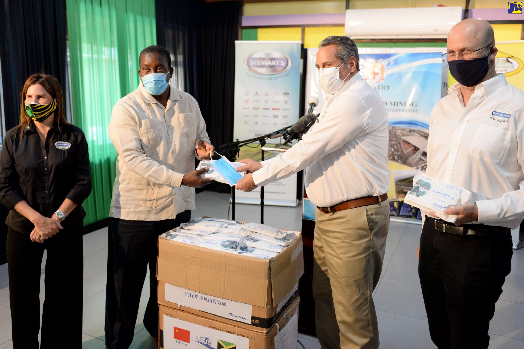 Transport and Mining Minister, Hon. Robert Montague (second left), presents a mask to Managing Director, Jamaica Urban Transit Company Limited (JUTC), Paul Abrahams (second right), at the handover of 9,900 masks to the Ministry of Transport and Mining recently, by Chinese commercial vehicle manufacturer, Zhengzhou Yutong Bus Company Limited, through local partner, Stewart