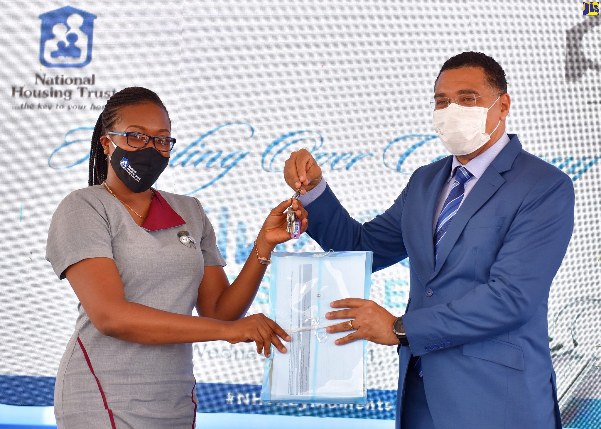 Prime Minister, the Most Hon. Andrew Holness (right), presents new homeowner, Treveen Palmer, with her keys at the National Housing Trust (NHT) development, SilverSun Estate, St. Catherine, recently.