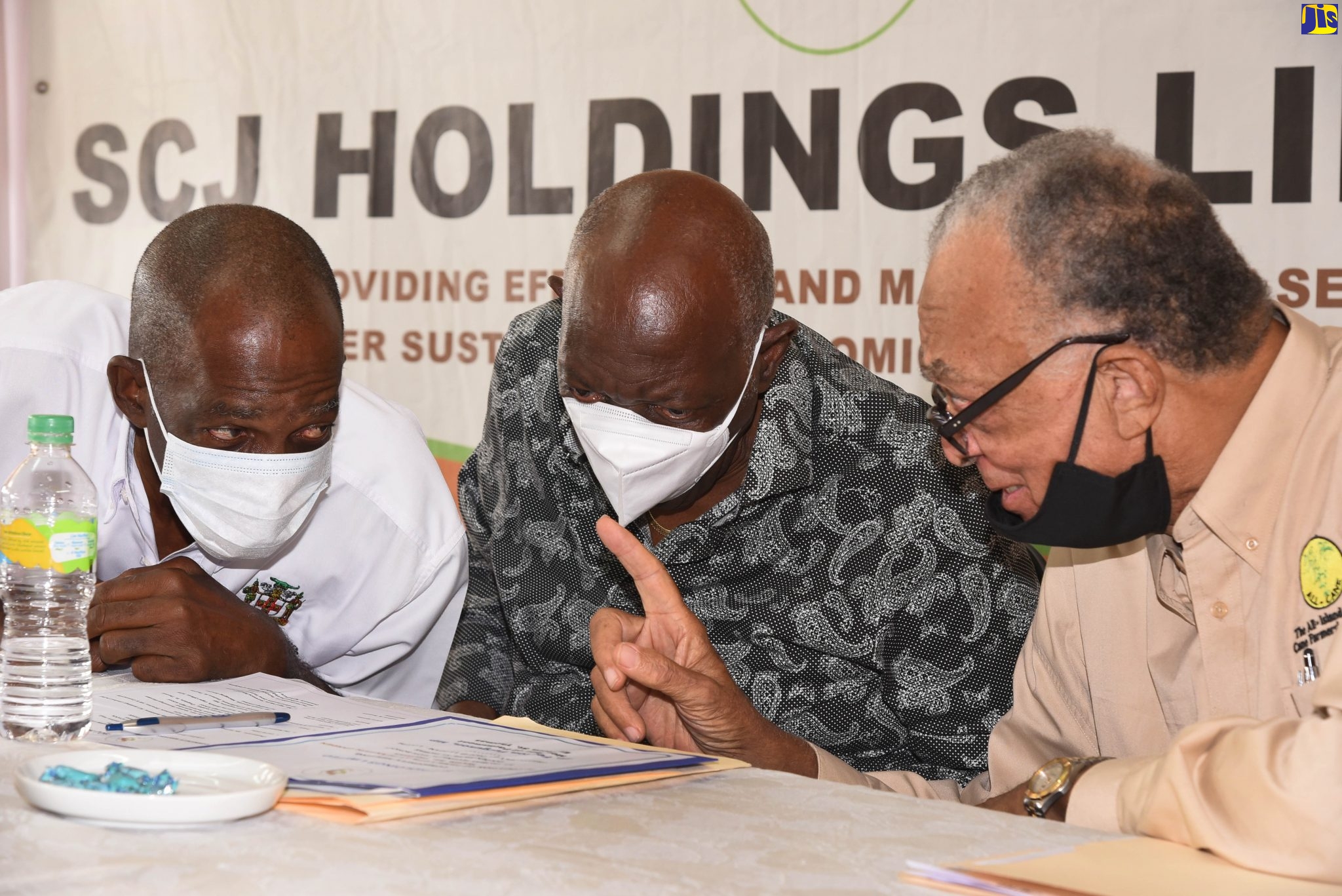 Minister without portfolio in the Ministry of Industry, Commerce, Agriculture and Fisheries, Hon. J.C. Hutchinson (left), converses with Member of Parliament for Eastern St. Thomas, Dr. Fenton Ferguson (centre), and Chairman of the All-Island Cane Farmers