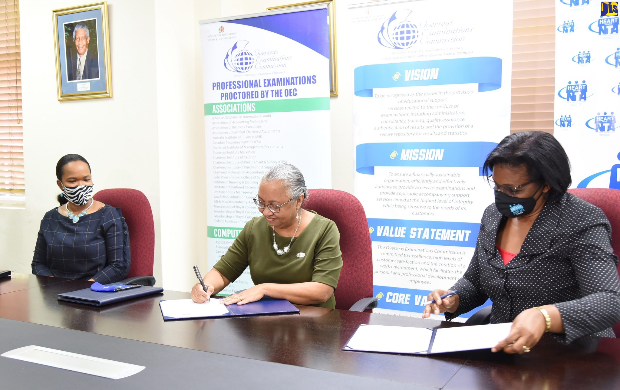 Managing Director of HEART/NSTA Trust, Dr.  Janet Dyer (right), along with Deputy Director of the Overseas Examinations Commission (OEC) with responsibility for the administration of examinations, Sharon Burnett (centre), sign a Memorandum of Understanding (MOU) for the OEC to administer the National Council on Technical and Vocational Education and Training (NCTVET) examinations for the period November 2019 to November 2022. Witnessing the signing (at left) is Acting Chief Education Officer in the Ministry of Education, Youth and Information, Dr. Kasan Troupe. The signing took place on July 23, at the OEC offices, 6 Manhattan Road, Kingston.