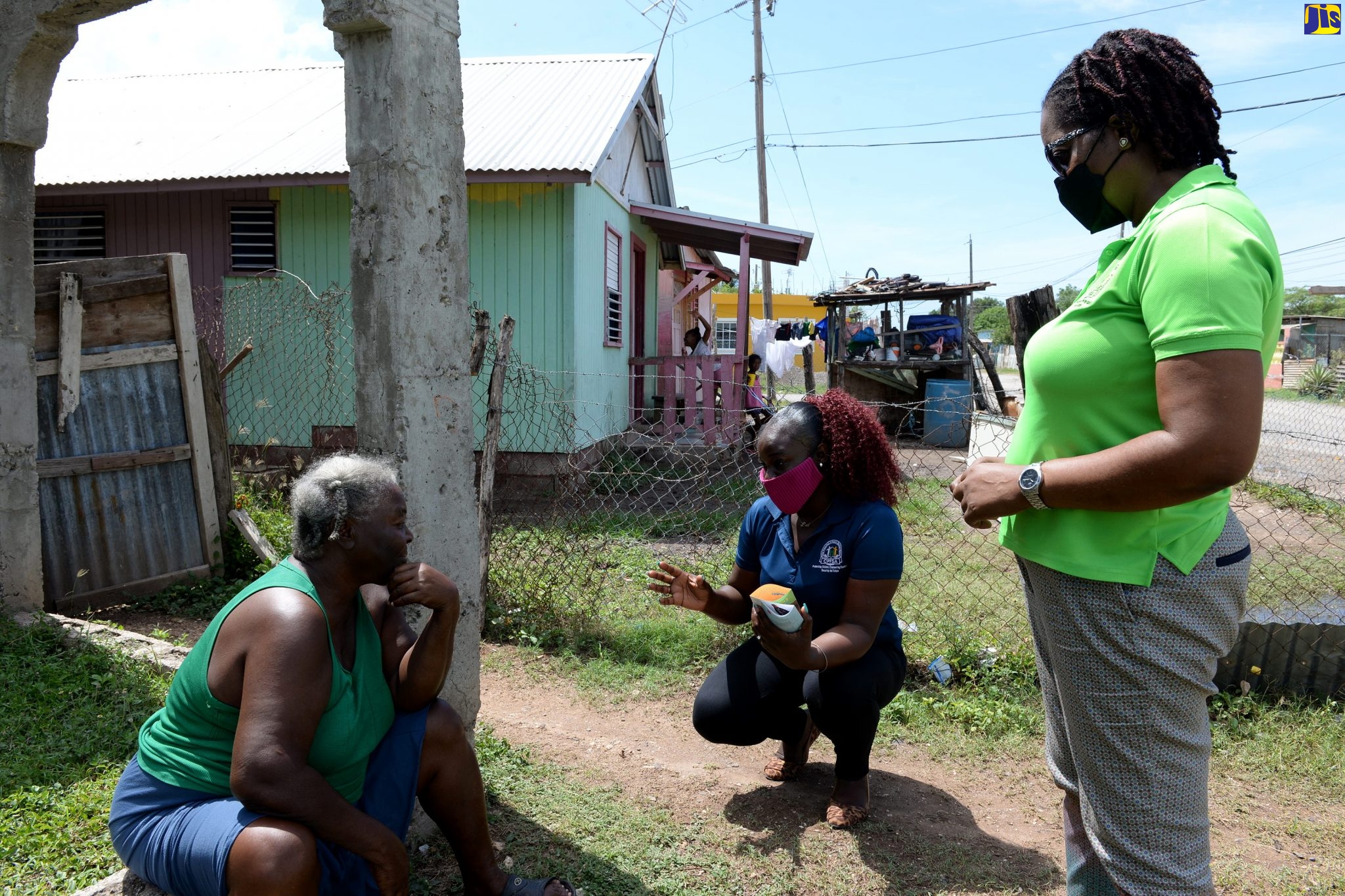 Public Relations Officer, Child Protection and Family Services Agency (CPFSA), Jeneva Gordon (centre), speaking with resident of Havana Heights, Clarendon, Hortense Parish (left), during a child protection drive-through in the community on July 1. Looking on is Regional Director, CPFSA, Francine Rhoomes.