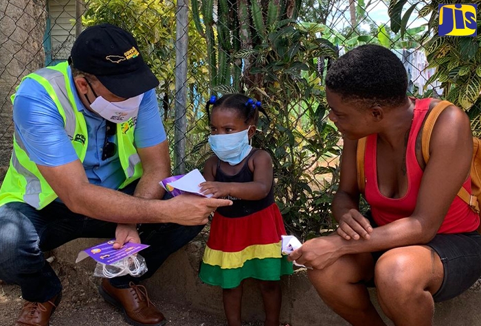 Minister of Health and Wellness, Dr. the Hon. Christopher Tufton, interacts with a toddler in the Bottom Town community in Clark