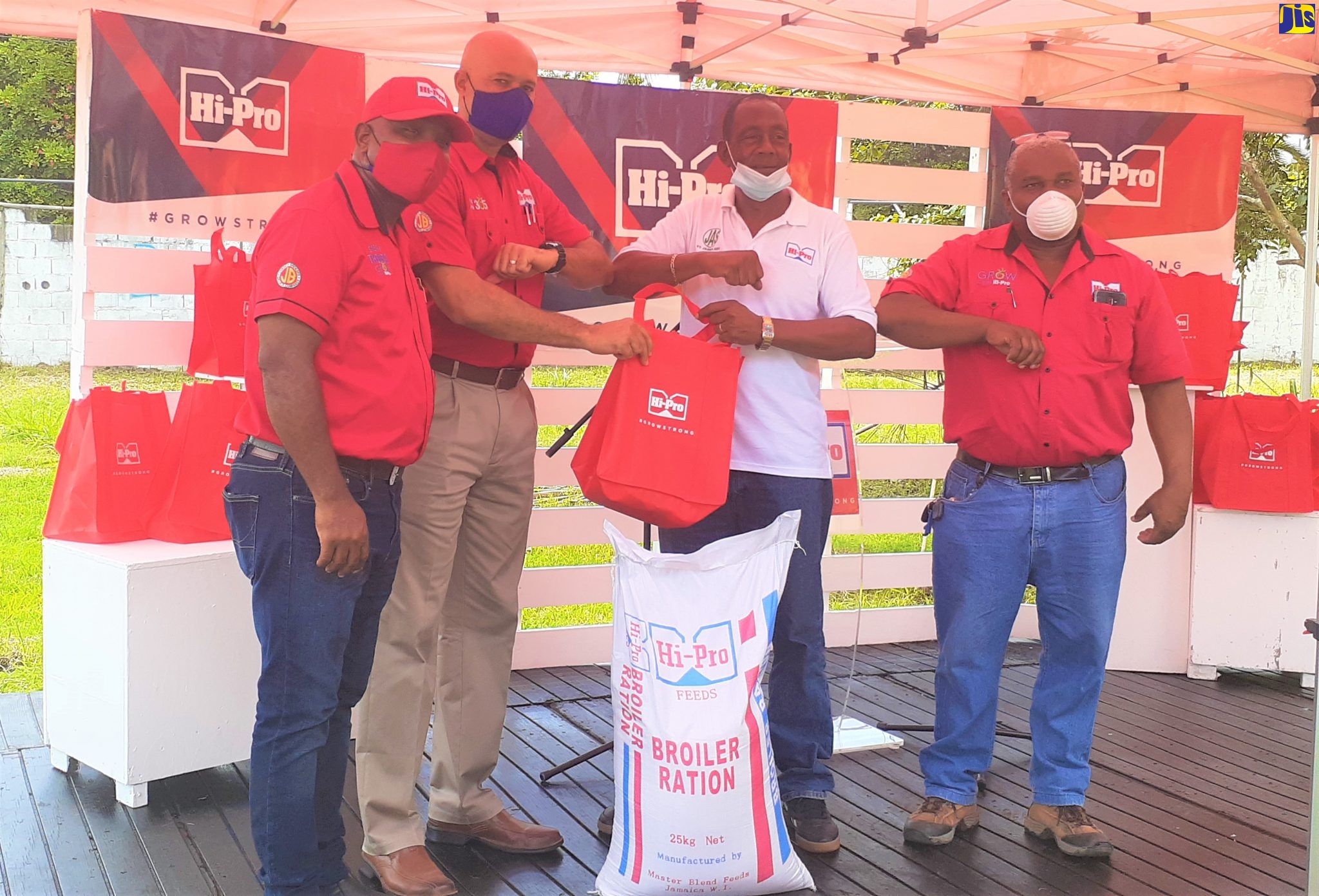 Vice President of Hi-Pro, Colonel Jaimie Ogilvie (second left) hands over a crop kit and Broiler Ration feed to President of the St. James Association of Branch Society (ABS) of the Jamaica Agricultural Society (JAS), Glendon Harris (second right), during the company’s donations handover ceremony, which was held at the Montpelier Agricultural Showground in St. James on July 10. Sharing in the moment are (from left) Technical Sales Representatives from Hi-Lo, Paul Thompson  and Garfield Russell.