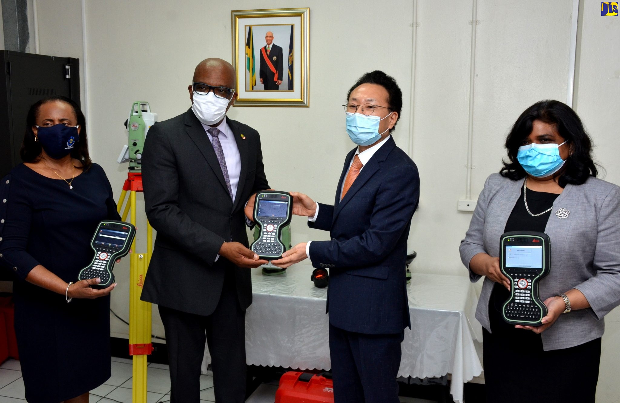 Former Minister without Portfolio in the Ministry of Economic Growth and Job Creation, with responsibility for Land, Environment and Climate Change, Hon. Leslie Campbell (second left), is presented with a Leica CS20 field controller by Chargé d’Affaires, Embassy of the Republic of Korea, Lim Baejin (second right), during the official handing over ceremony for several pieces cadastral mapping and land surveying equipment, on Thursday (July 16) at the National Land Agency Estate Management Division, Downtown, Kingston. Also displaying the devices are Chief Executive Officer, National Land Agency (NLA) Elizabeth Stair (left) and Under-Secretary, Bilateral, Regional and Hemispheric Affairs in the Ministry of Foreign Affairs and Foreign Trade, Ambassador Janice Miller.  Mr. Campbell has since been re-assigned to the Ministry of Industry, Commerce, Agriculture and Fisheries.