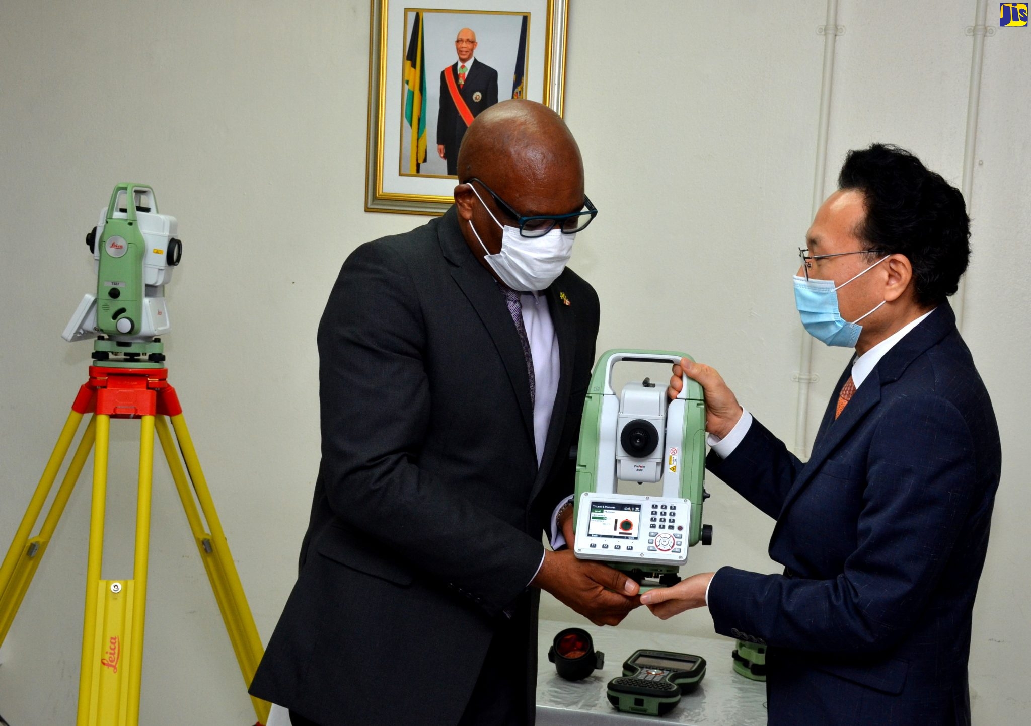Minister without Portfolio in the Ministry of  Economic Growth and Job Creation, with responsibility for Land, Environment and Climate Change, Hon. Leslie Campbell (second left), is presented with a Leica CS20 field controller by Chargé d’Affaires, Embassy of the Republic of Korea, Lim Baejin, at the official handover of cadastral mapping and land surveying equipment, on Thursday (July 16), at the National Land Agency Estate Management Division, downtown Kingston.