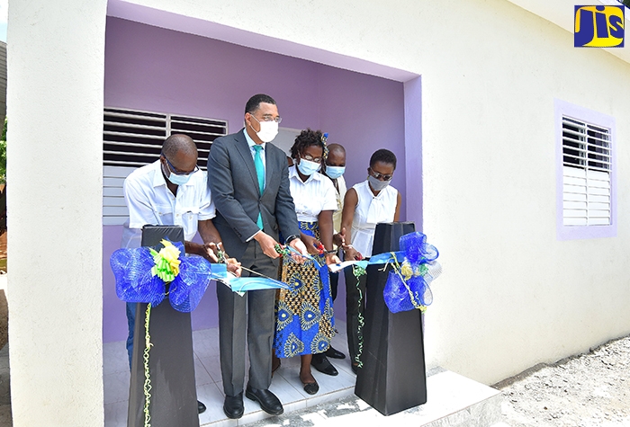 Prime Minister, the Most Hon. Andrew Holness (second left), joins in cutting the ribbon to officially hand over a three-bedroom house to Melissa Smith (centre), in Old Harbour Bay, St. Catherine, on Thursday (July 30). Others (from left) are Member of Parliament for South West St. Catherine, Hon. Everald Warmington;  Councillor for the Old Harbour South Division, Lloyd Grant; and Chief Technical Director in the Ministry of Economic Growth and Job Creation, Doreen Prendergast.The unit was provided under the Government