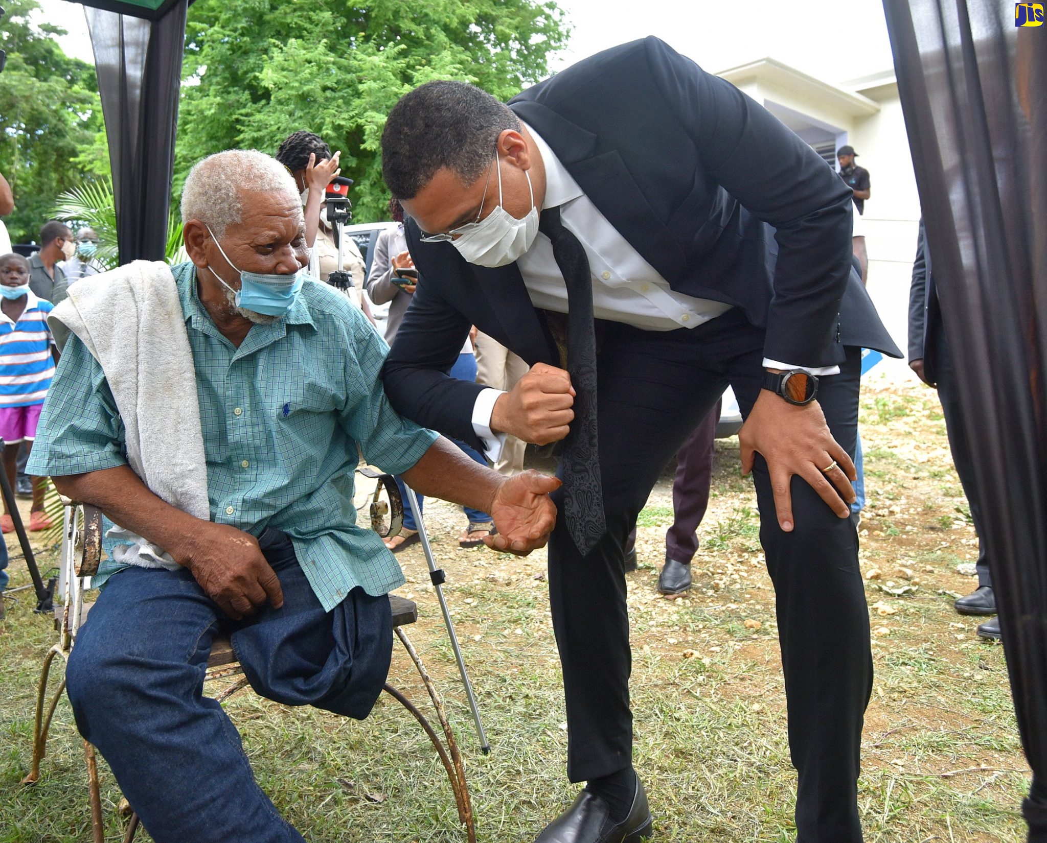 Prime Minister, the Most Hon. Andrew Holness (right),  congratulates 88 year-old Winston Wint (in wheelchair) on receiving a one bedroom housing unit, courtesy of the Government’s New Social Housing Programme (NSHP),at a handing over ceremony in Bogue District, St. Elizabeth, on July 17. Mr. Wint also received  a new wheelchair.