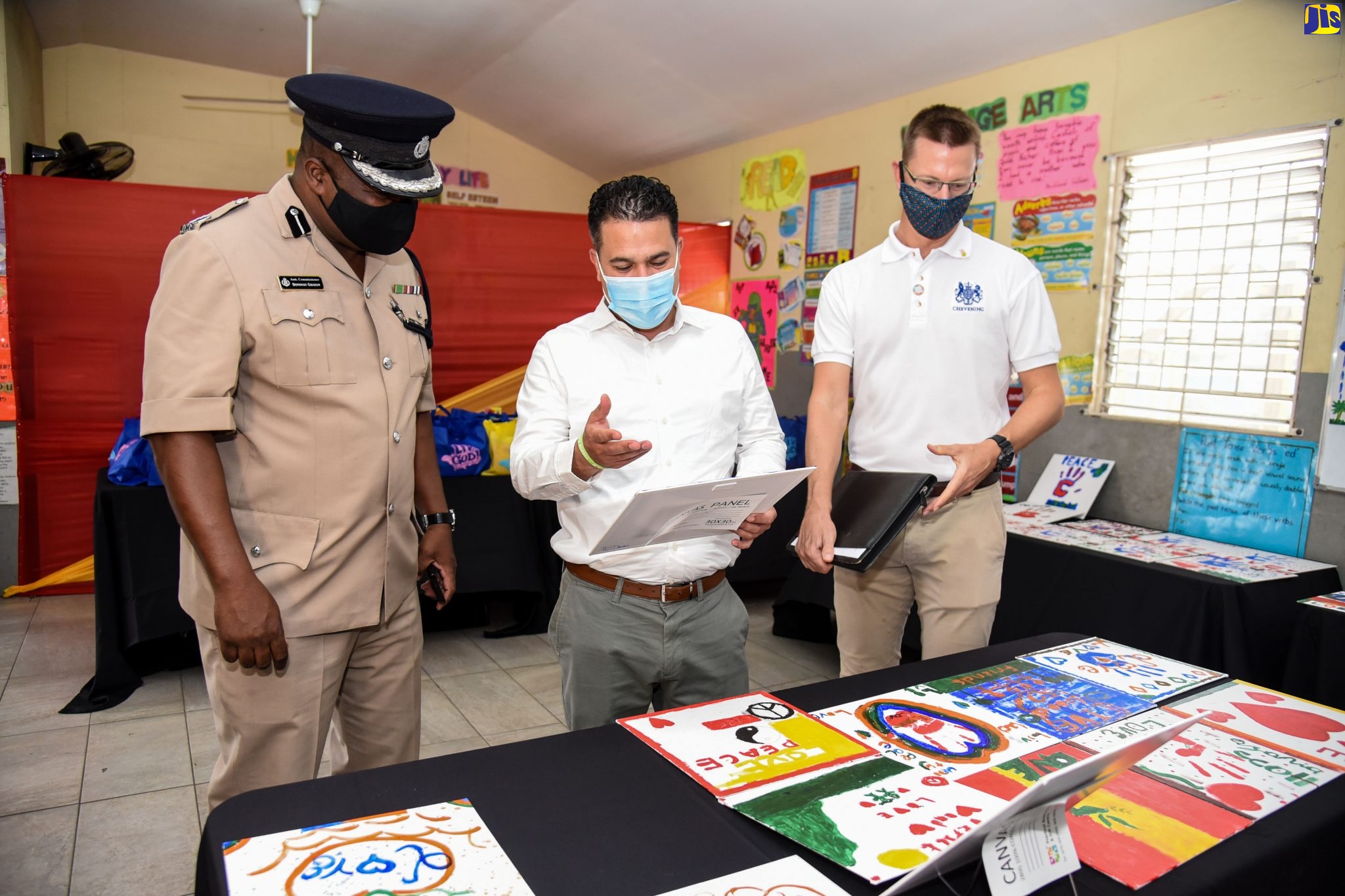 Minister without Portfolio in the Ministry of National Security, Senator Hon. Matthew Samuda (centre), highlights features of a drawing done by a student, to Assistant Commissioner of Police, Donovan Graham (left). At right, Country Representative, Department for International Development (DFID), David Osborne, looks at other works of art on display. Occasion as the closing out ceremony and exhibition for the summer programme held at the Dupont Primary and Infant School in St. Andrew on July 31. The programme was organised by the Ministry under its