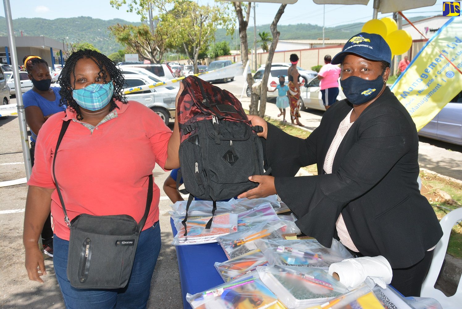 Regional Administrator, Western Parks and Markets (WPM) Waste Management Limited, Karen Clayton (right), hands over a shool bag to street sweeper, Tamara Chambers, during a book drive and back-to-school treat, staged by the entity, at the Sagicor Commercial Complex in Montego Bay on Friday (August 21).