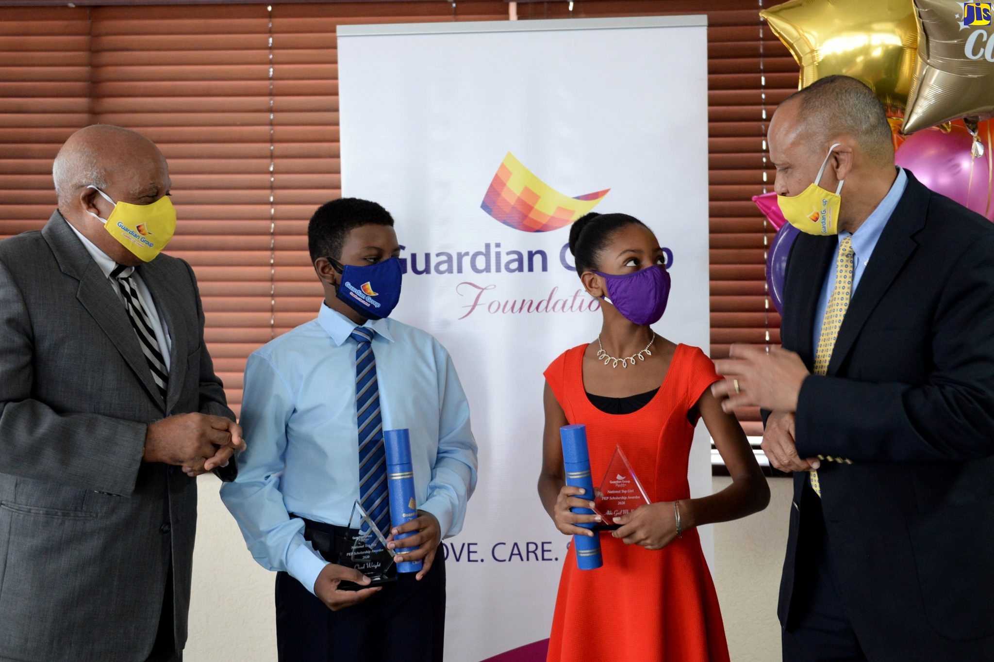 President of Guardian Life Limited, Eric Hosin (right), speaks with top-performing girl and boy in the Primary Exit Profile (PEP) Abigail McKenzie (second right) and Chad Wright (second left), during the Guardian Group Foundation’s annual Scholarship and Grant Awards ceremony held on Wednesday (August 12), at the company
