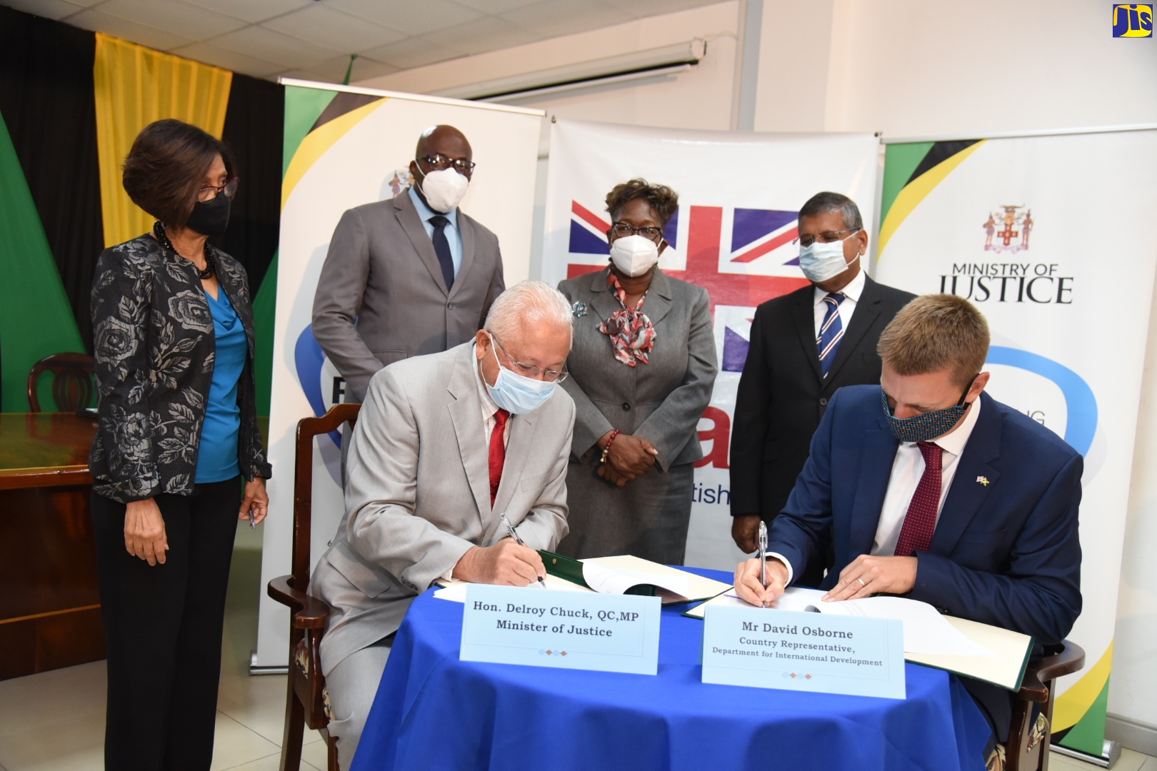 Minister of Justice, Hon. Delroy Chuck (seated left), signs a Memorandum of Understanding (MOU) with Country Representative, Department for International Development (DFID), David Osborne (seated right), at the Ministry in Kingston on Tuesday (August 11). The agreement, valued at £1,000,000, is intended to strengthen Jamaica’s anti-corruption framework by building the capacity of select institutions to improve accountability and transparency. Witnessing the signing (standing from left) are Permanent Secretary, Ministry of Justice, Sancia Bennett Templer; Chief Justice, Bryan Sykes; Director of Public Prosecutions (DPP), Paula Llewellyn; and British High Commissioner to Jamaica, His Excellency, Asif Ahmad.