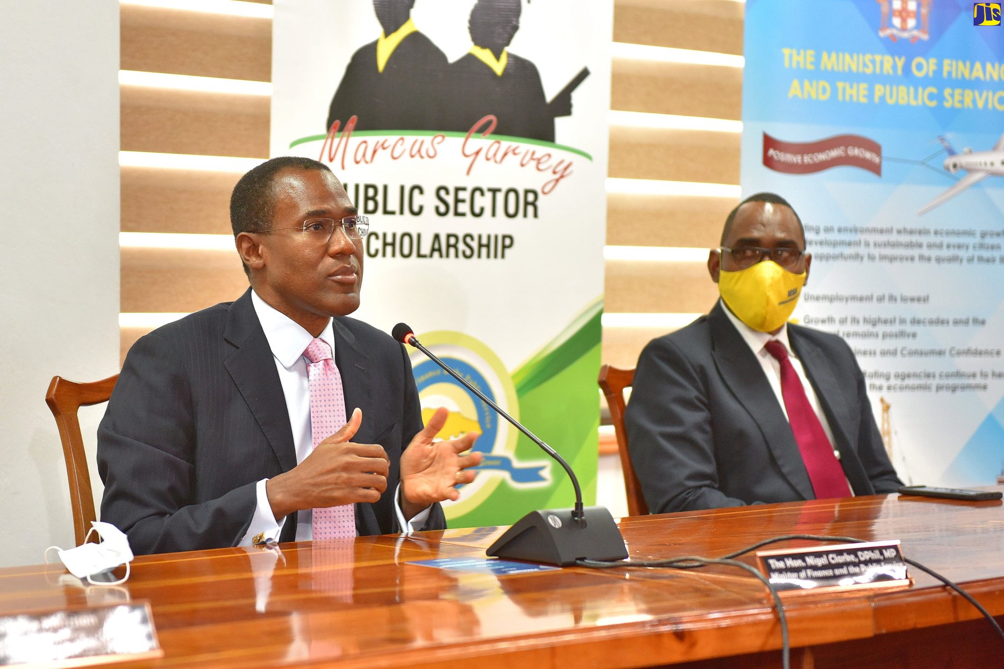 Minister of Finance and the Public Service, Dr. the Hon. Nigel Clarke (left), speaking at the recent virtual launch of the Marcus Garvey Public Sector Scholarship Programme at the Ministry's offices in Kingston. Listening is Jamaica Civil Service Association President, O'Neil Grant .