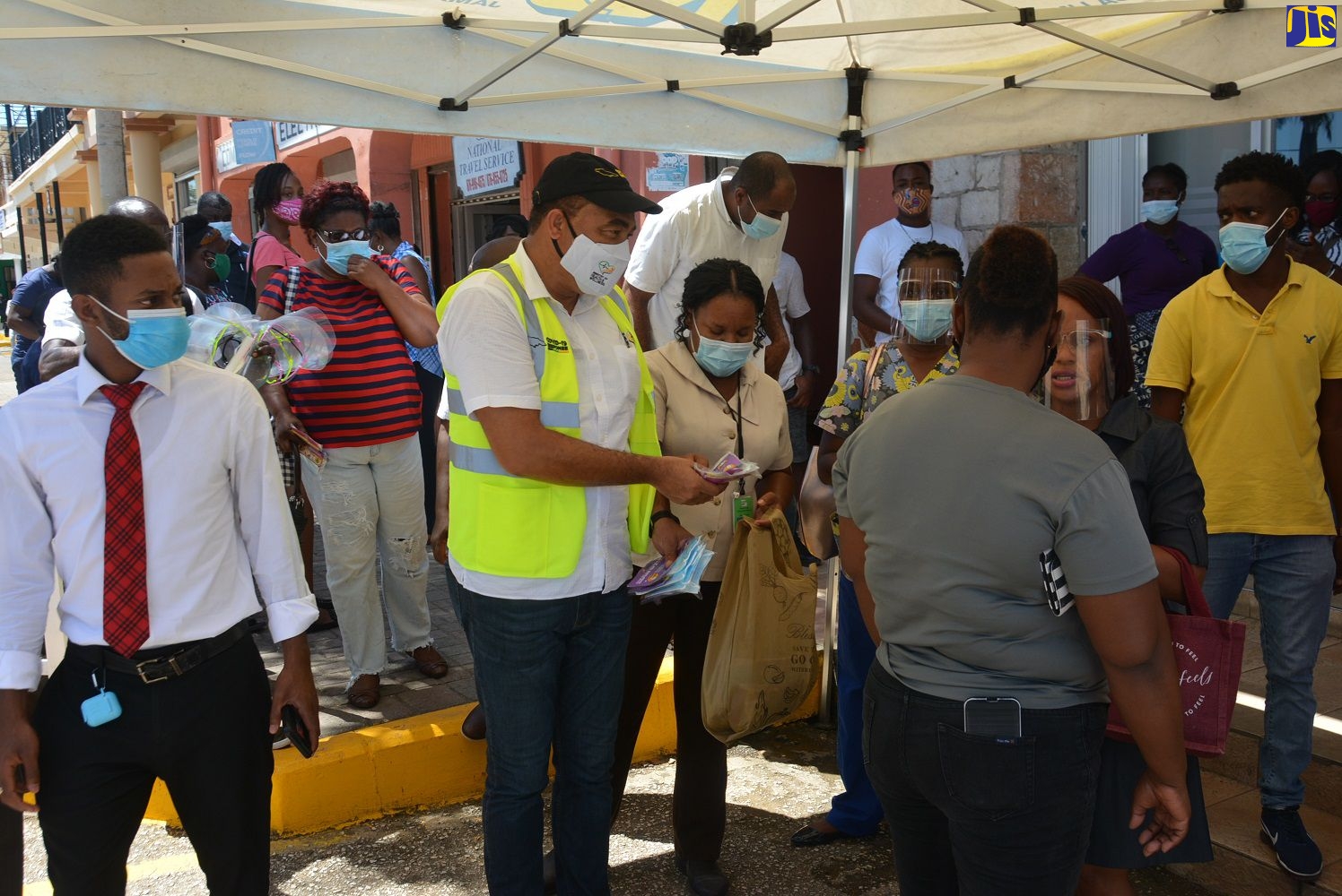 Minister of Health and Wellness, Dr. the Hon. Christopher Tufton, hands out face masks and health information to residents in Falmouth on Friday (September 25)