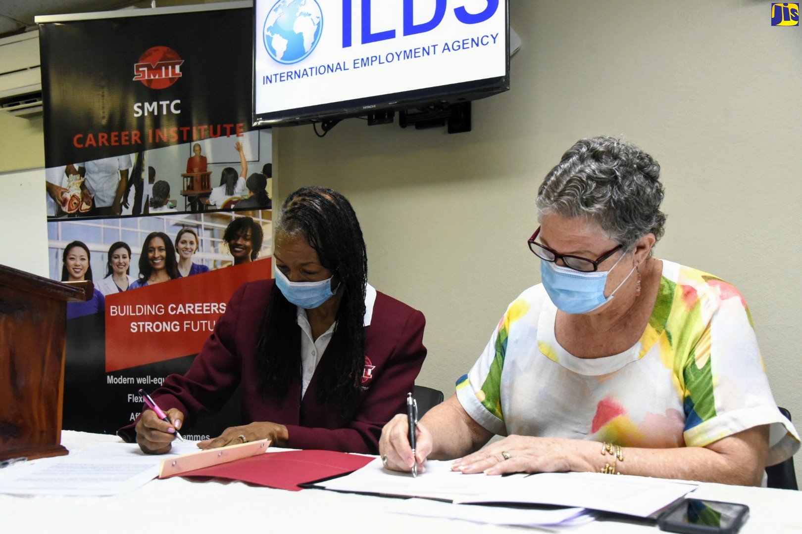 Principal, Strategic Management and Training Consultants Ltd (SMTC) Career Institute, Beverley Dinham Spencer (left); and Director, Mona Ageing and Wellness Centre, Professor Denise Eldemire-Shearer, affix their signatures to a memorandum of understanding (MOU) at the ILDS International Employment Agency, Seymour Park in St. Andrew, today (September 10). The institutions will collaborate on the development and delivery of an advanced Patient Care Technician Certificate training course.