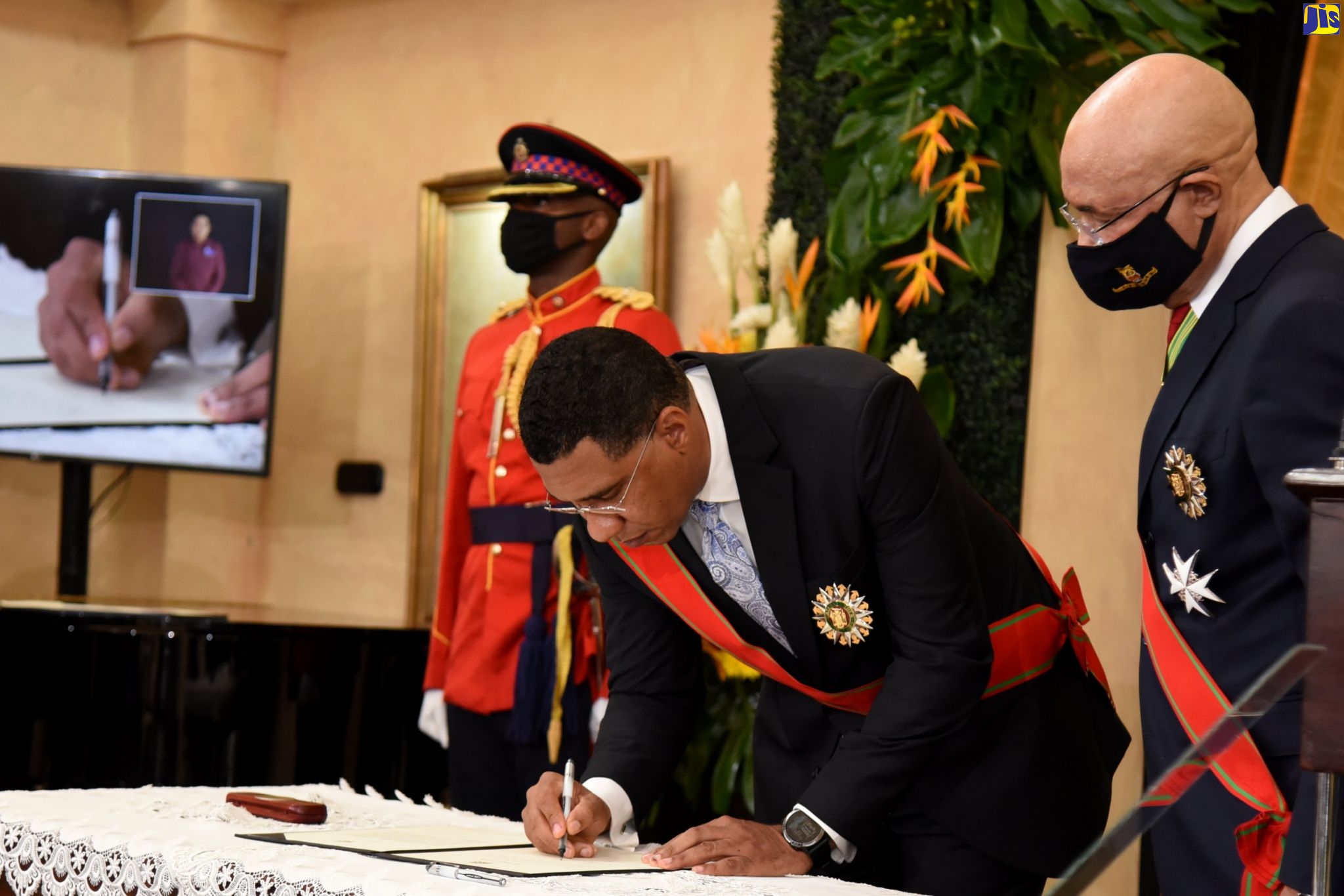 Prime Minister, the Most Hon. Andrew Holness (second right), signs his Instrument of Appointment during the swearing-in ceremony at King