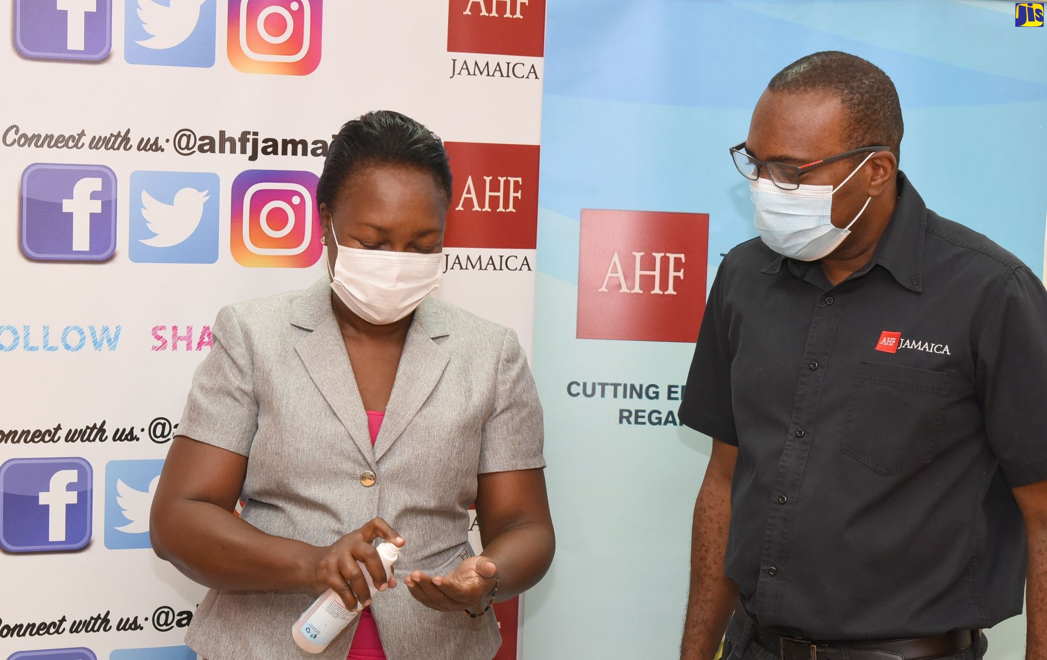 Principal, Penwood High School, Donna McLaren (left), tries out a bottle of hand sanitiser, while Caribbean Regional Director for the AIDS Healthcare Foundation (AHF), Dr. Kevin Harvey, looks on. Occasion was a ceremony for the donation of book vouchers, hand sanitisers and face masks to benefit students of Penwood High and Cockburn Gardens Primary, at the AHF