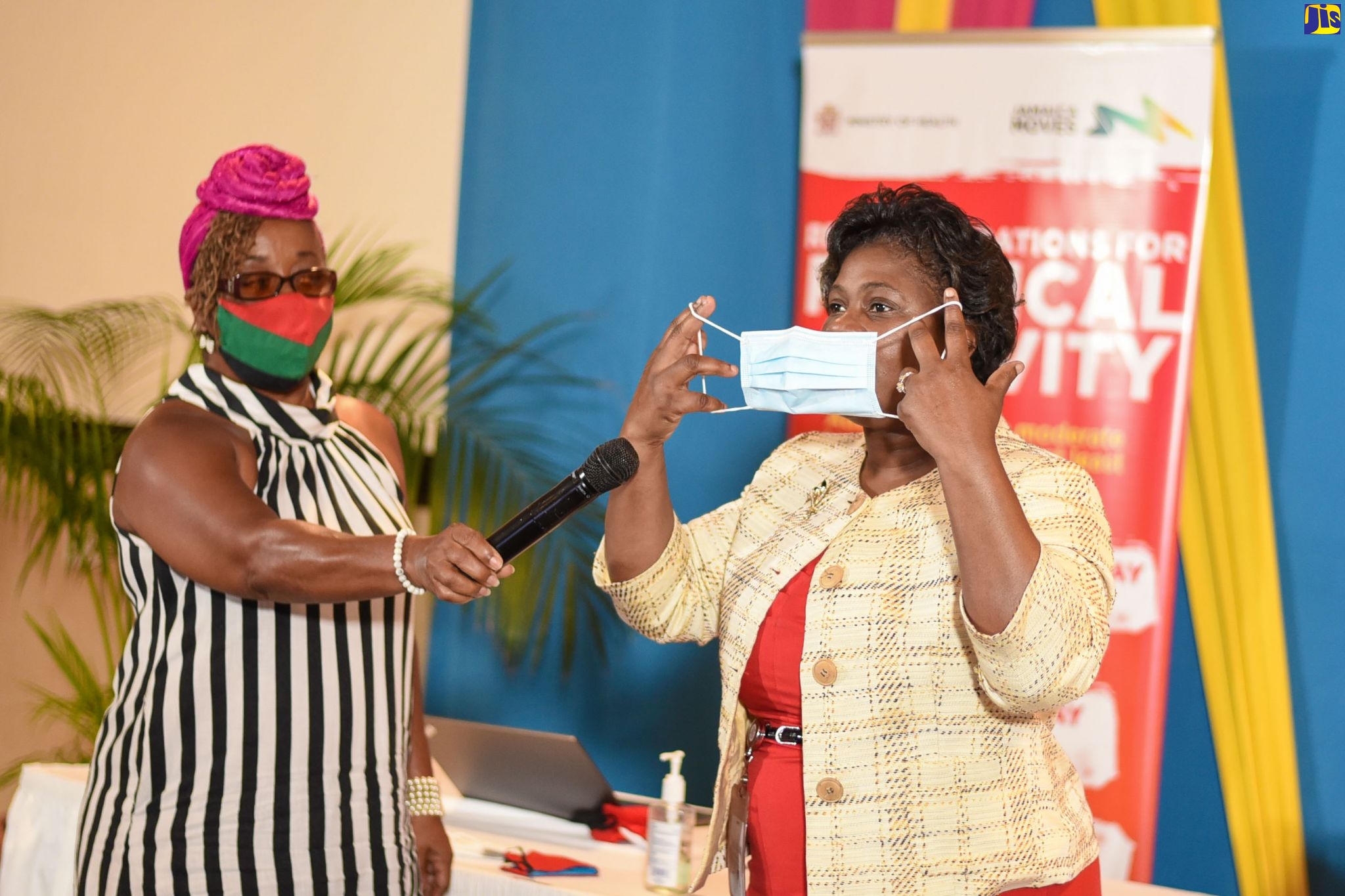 Deputy Chief Nursing Officer in the Ministry of Health and Wellness, Karen Nelson (right), demonstrates how to correctly put on and remove a mask during her presentation at a Senior Citizens Wellness Webinar, held at The Jamaica Pegasus hotel on Thursday (October 1). Also pictured is host for the event, Rosie Murray. It was staged by the Ministry of Health and Wellness, in collaboration with the Ministry of Labour and Social Security and the National Council for Senior Citizens.