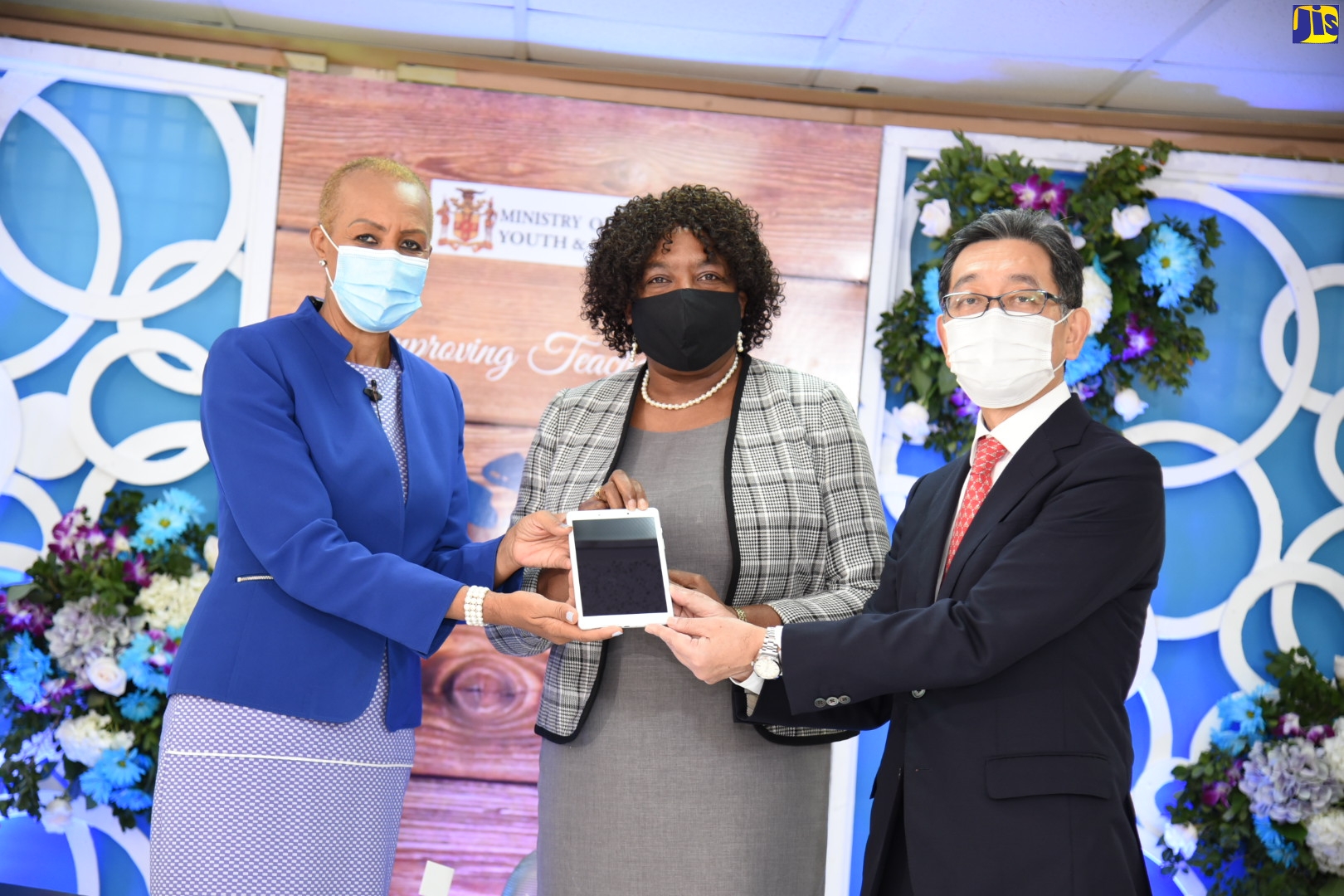 Minister of Education, Youth, and Information, Hon. Fayval Williams (left), and Ambassador of Japan to Jamaica, His Excellency Masaya Fujiwara (right), present Dean, Faculty of Education, the Mico University College, Karren Foster, with one of 100 tablets being distributed under a capacity-building project benefiting 10 teacher training institutions. The presentation took place during a virtual ceremony to officially launch internal quality assurance standards for teacher education institutions on Friday (Oct. 30).