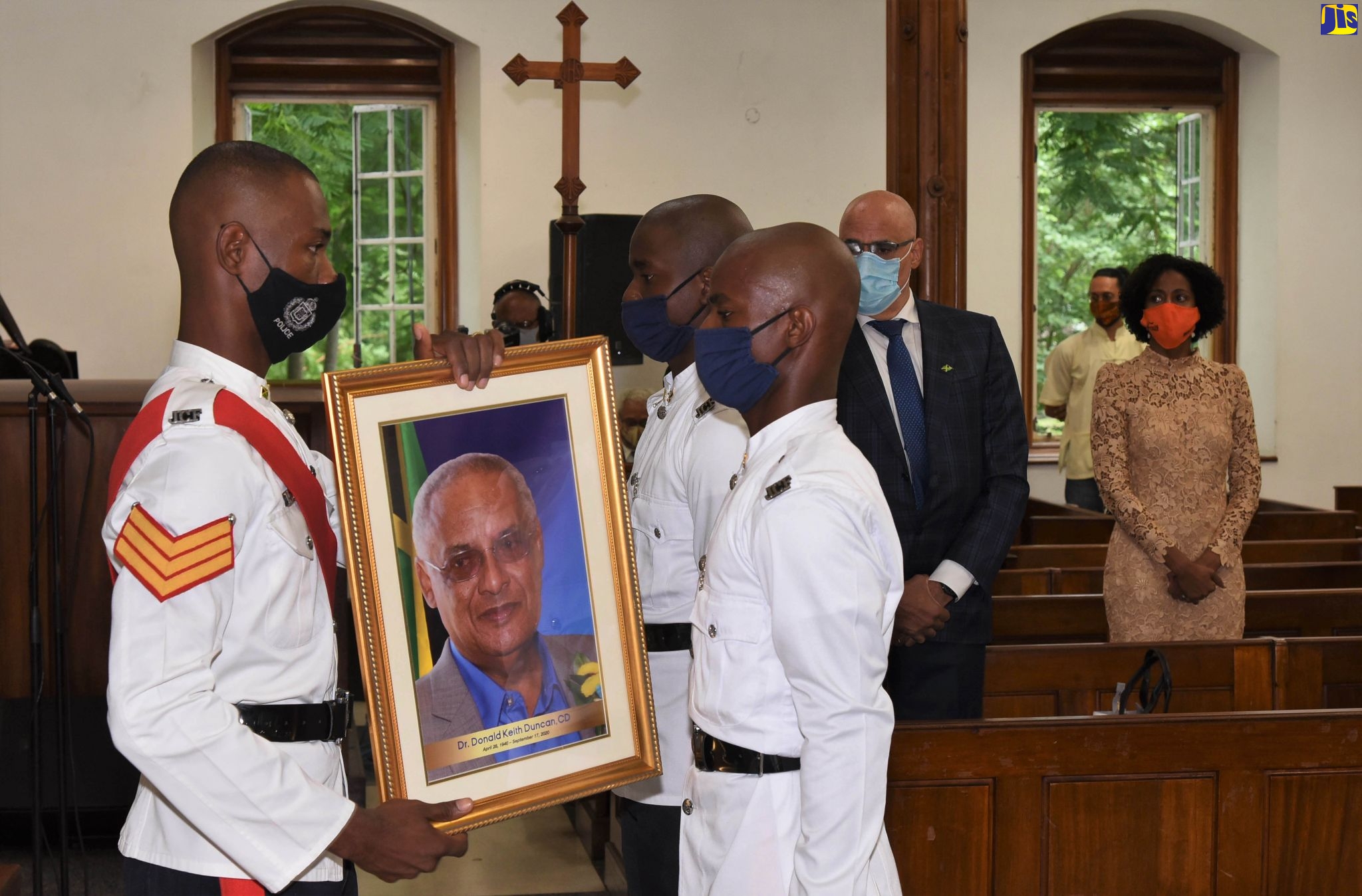 Members of the Jamaica Constabulary Force (JCF), carry a framed photograph of late former Cabinet Minister and Member of Parliament, Dr. D.K. Duncan, inside the University Chapel in St. Andrew on Sunday (Octpber 25), where his official memorial was held.