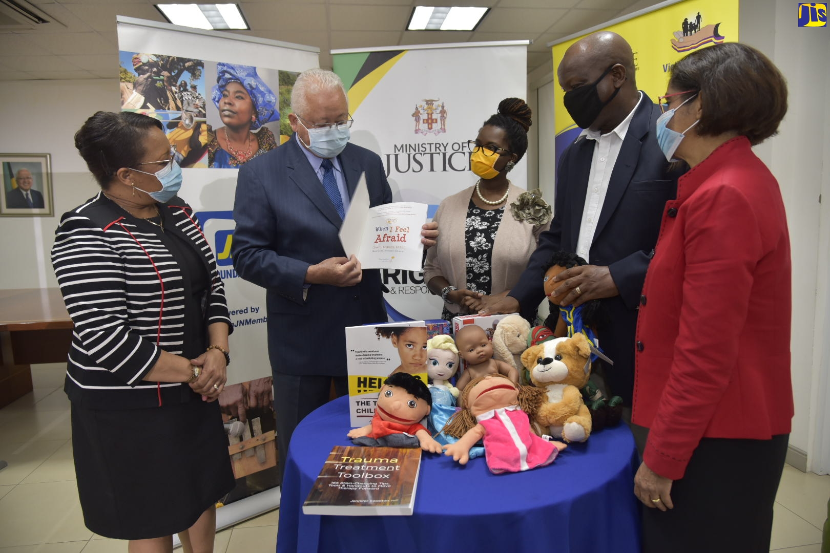 Justice Minister, Hon. Delroy Chuck (second left), peruses a book during the handover of play therapy tools for children by the Jamaica National (JN) Foundation to the Ministry’s Victims Services Division (VSD) on Friday (October 16). Others (from left) are: Chief Technical Director in the Ministry, Grace-Ann Stewart-McFarlane; General Manager, JN Foundation, Onyka Barrett-Scott; Director, VSD, Osbourne Bailey; and Permanent Secretary in the Ministry, Sancia Bennett-Templer.