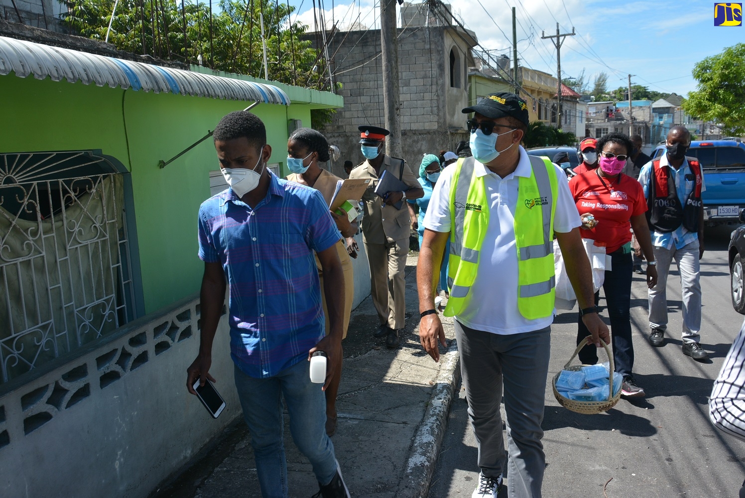 Minister of Health and Wellness, Dr. the Hon. Christopher Tufton (right), leading a tour in the Cornwall Courts community in St. James on Friday, October 30, where he handed out face masks and hand sanitizers to residents. A special area curfew is imposed on the community from October 23 to November 6 due to a rise in the number of positive COVID-19 cases in the area.