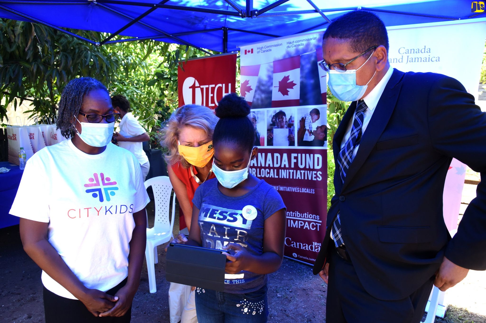 Grade-Four student of St. George’s Girls School, Daviqua Brown (third left), tests one of 24 tablets handed over by the High Commission of Canada to local, non-profit organisation City Life Ministries for its ‘City Kids’ programme. The programme seeks to provide information and communications technology (ICT) and other academic support to inner-city youth to assist the virtual learning environment. The tablets were handed over at an official ceremony held on Thursday (October 1) in Parade Gardens in Kingston. Sharing the moment (from left) are Parent-Teacher for the City Kids Programme, Paula Smith; Canadian High Commissioner to Jamaica, Her Excellency Laurie Peters; and Member of Parliament for Central Kingston, Donovan Williams.


