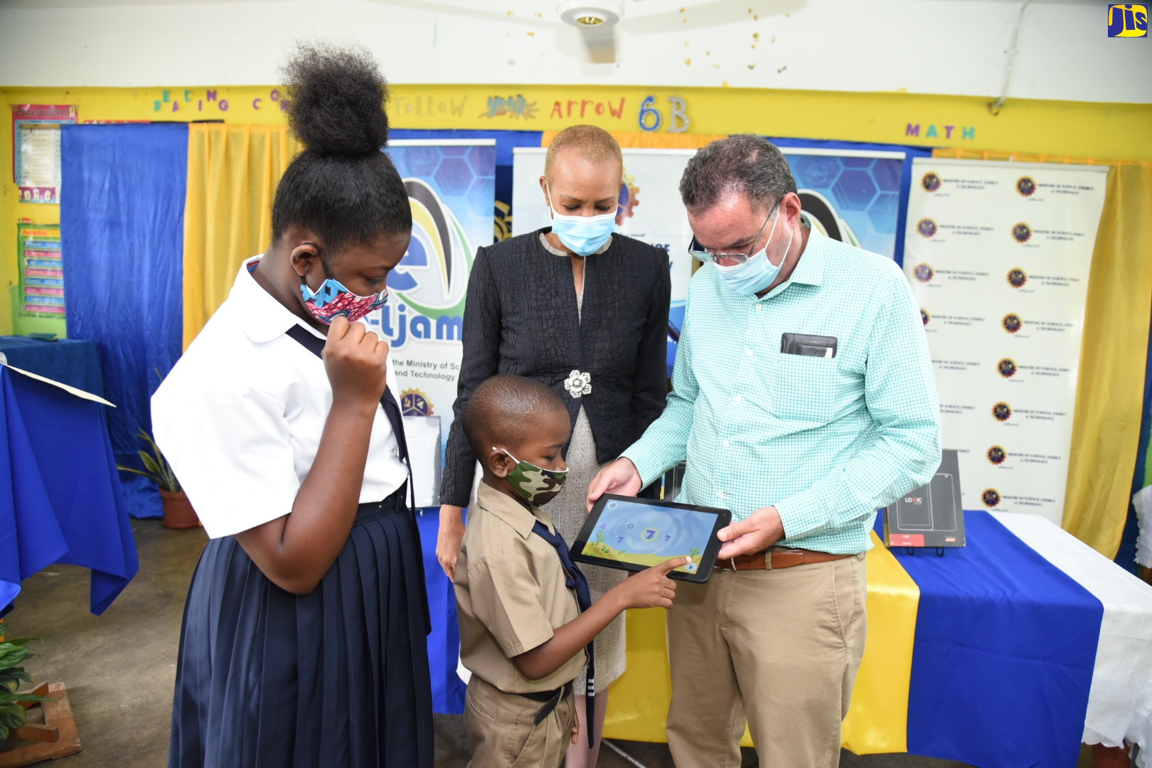 Minister of Science, Energy and Technology, Hon. Daryl Vaz (right), assists Buff Bay Primary School student, Brandon Parkes (second right), as Brandon interfaces with the new tablet, which he received during a handover ceremony at the school on Thursday (October 22). Looking on are Minister of Education, Youth and Information, Hon. Fayval Williams and student, Tiona Watson.