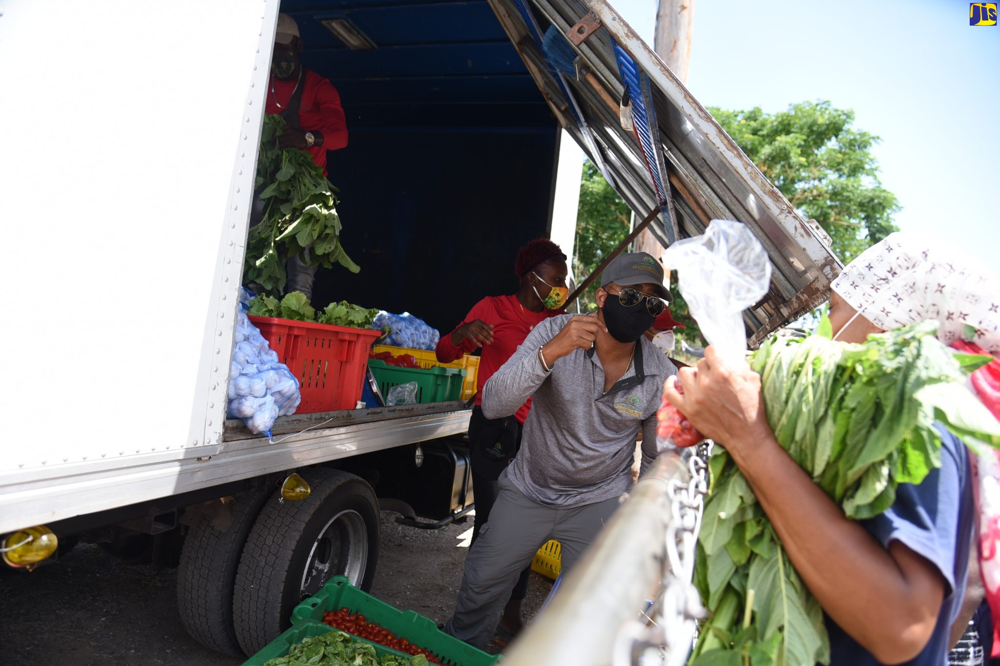 A vendor (centre) assists a customer purchasing ground provisions during a farmers’ market in Kingston.

