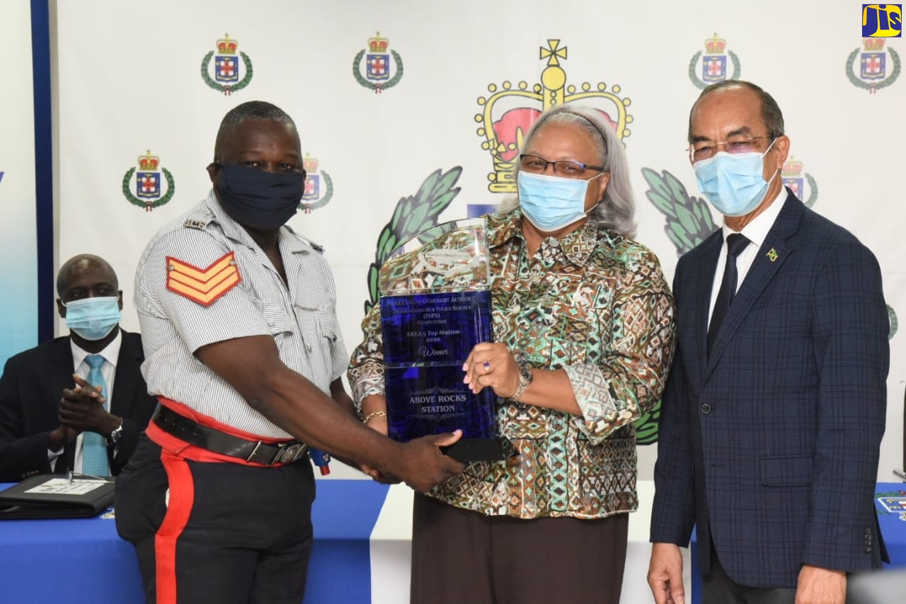Minister of National Security, Hon. Dr. Horace Chang  (right), looks on while Sergeant Garfield Wallace (left) of the Above Rocks Police Station in St. Catherine, receives the Police Civilian Oversight Authority (PCOA) Transforming Our Police Service (TOPS) award for Top Station in Area 5, from Chairman of the PCOA, Jacquiline Hickson (centre). Occasion was the 2020 awards ceremony, held at the  Office of the Police Commissioner, St. Andrew, on Wednesday (November 25).