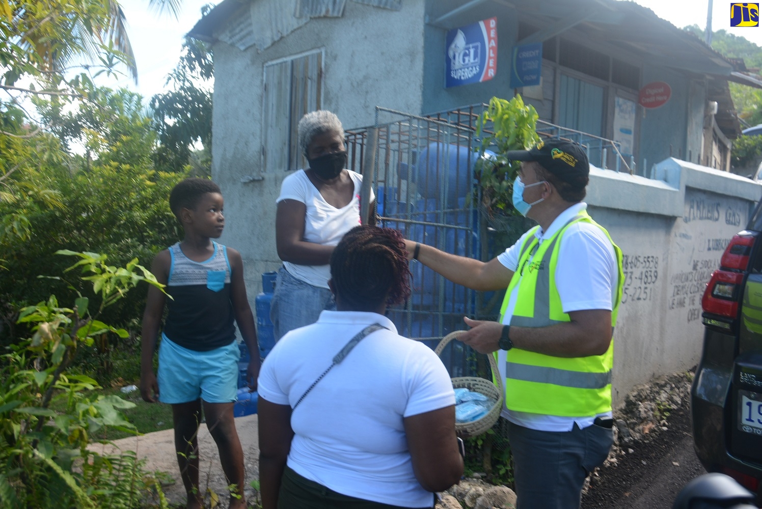 Minister of Health and Wellness, Dr. the Hon. Christopher Tufton (right), hands out face masks and hand sanitisers to residents in Moy Hall, St. James, on Friday, October 30.