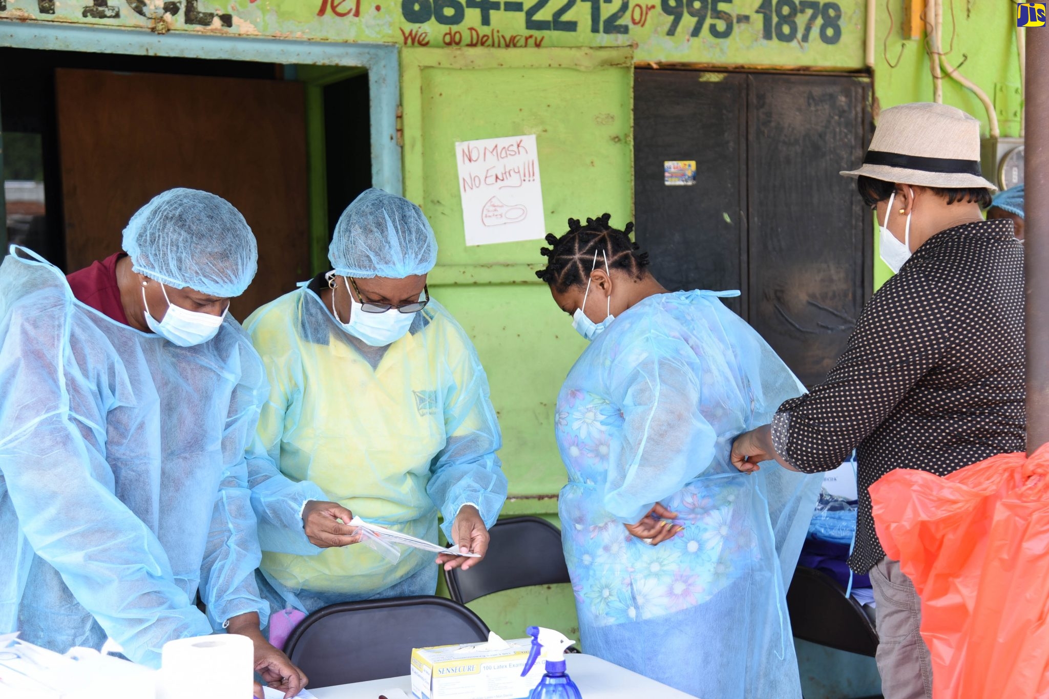 Senior Public Health Nurse, St. Catherine Public Health Department, Marlene Stephenson (right), helps health workers to don protective gear as they prepare to do coronavirus (COVID-19) testing in the Church of God of Prophecy in Frazer’s Content in Spanish Town, St. Catherine on Saturday (Nov. 21). The exercise, which included house-to-house surveillance and sensitisation, was part of strategic intervention to curtail the spread of the virus.