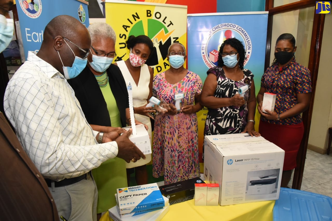 Board Member, Usain Bolt Foundation, Stephen Shaw (left); and Chairman of the Foundation, Winsome Wilkins (2nd left);  look at one of the items donated by the Foundation to 21 Early Childhood Institutions (ECI) across five parishes, at the Early Childhood Commission