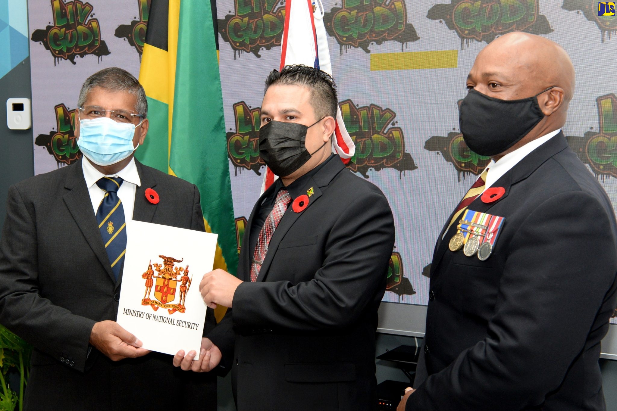 Minister without Portfolio in the Ministry of National Security, Senator the Hon. Matthew Samuda (centre), hands over a report on the implementation of the ‘Jamaica Strategic Corrections Partnership Project’ to United Kingdom (UK) High Commissioner to Jamaica, His Excellency Asif Ahmad, during a brief presentation ceremony at the Ministry’s offices in New Kingston on November 11. The project, which was initiated in 2017 with funding support of £620,000 from the UK’s Foreign, Commonwealth and Development Office and concluded recently, was undertaken to improve the Department of Correctional Service’s (DCS) operational capacity, reduce recidivism among offenders, and provide ex-offenders with community reintegration support. All 11 of the island’s correctional facilities and several ex-offenders benefitted from the donation, which was channeled through the UK’s Conflict, Stability and Security Fund that operates globally. Looking on is Commissioner of Corrections, Lt. Col. (Retired) Gary Rowe.