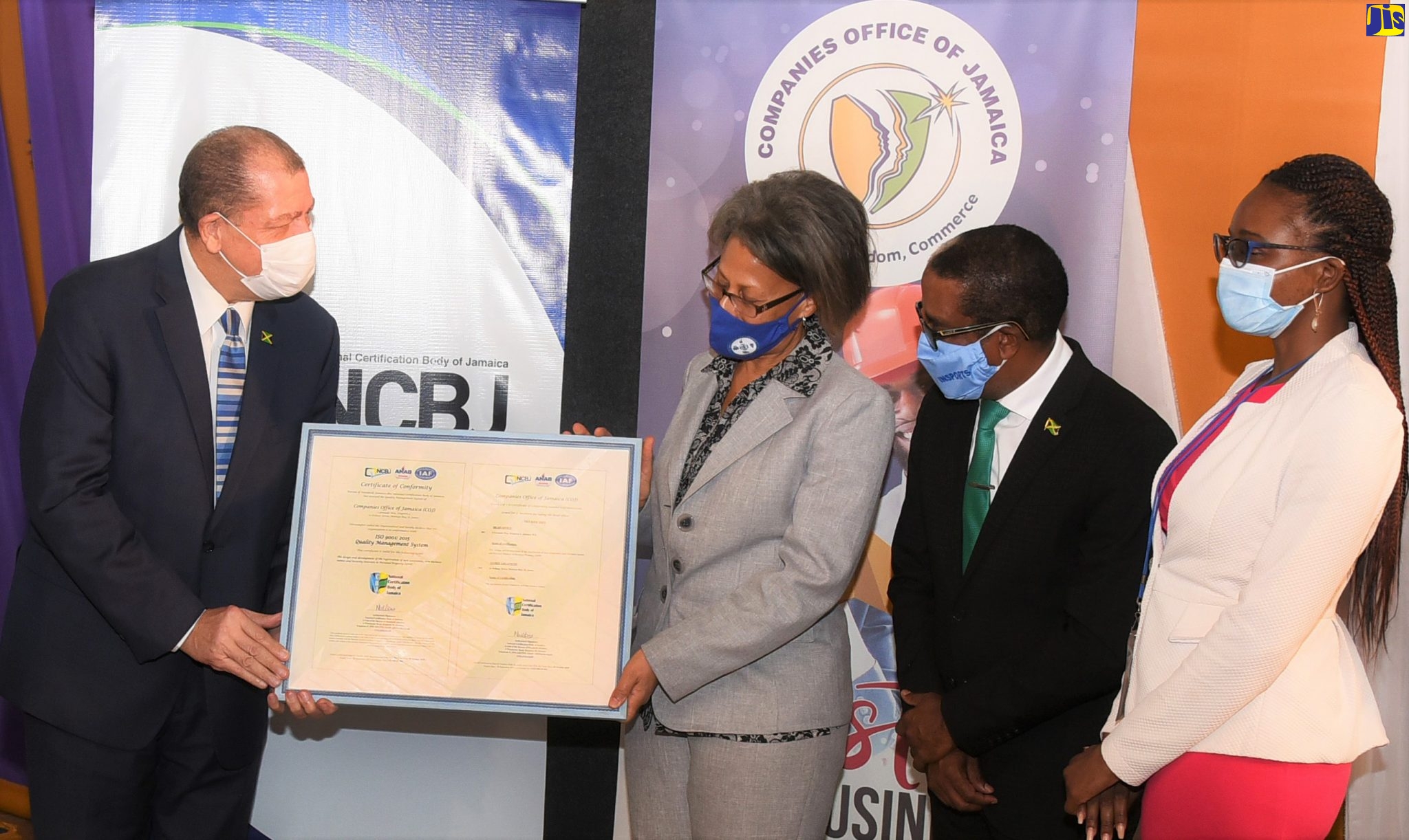 Minister of Industry, Investment and Commerce, Hon. Audley Shaw (left); presents Chief Executive Officer of the Companies Office of Jamaica (COJ), Judith Ramlogan, with the document officially certifying the COJ as ISO 9001:2015 Quality Management System-compliant. The presentation was made during a ceremony hosted by the National Certification Body of Jamaica (NCBJ) at its offices at the Bureau of Standards Jamaica (BSJ), Winchester Road, St. Andrew, on Thursday (November 12). Sharing the moment are State Minister in the Industry, Investment and Commerce, Dr. the Hon. Norman Dunn (second right); and the COJ’s Corporate Planner and Quality Monitoring Officer and ISO Project Manager, Cyleena Gray.