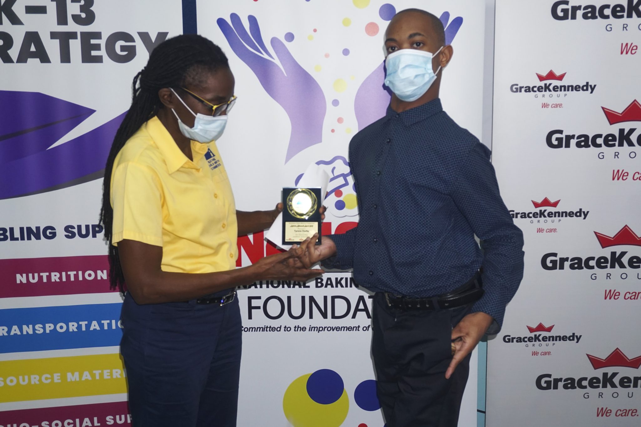Vice-Chairman of the National Child Month Committee (NCMC), Sandrea Long-White,  presents 18-year-old Tyrone Darby with his award for his achievement in the Caribbean Secondary Education Certificate (CSEC) examinations, in November.

