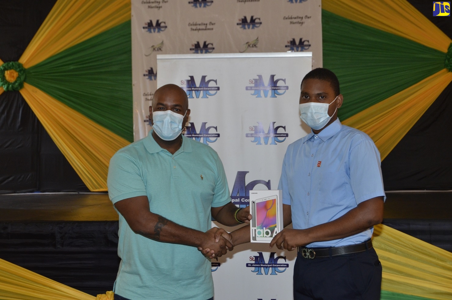 Councillor for the Spring Garden Division in St James, Dwight Crawford (left), presents a tablet computer to student of the Montego Bay Community College, Marlon Rowe,  during a handover exercise at the Montego Bay Cultural Centre on Wednesday (December 16).