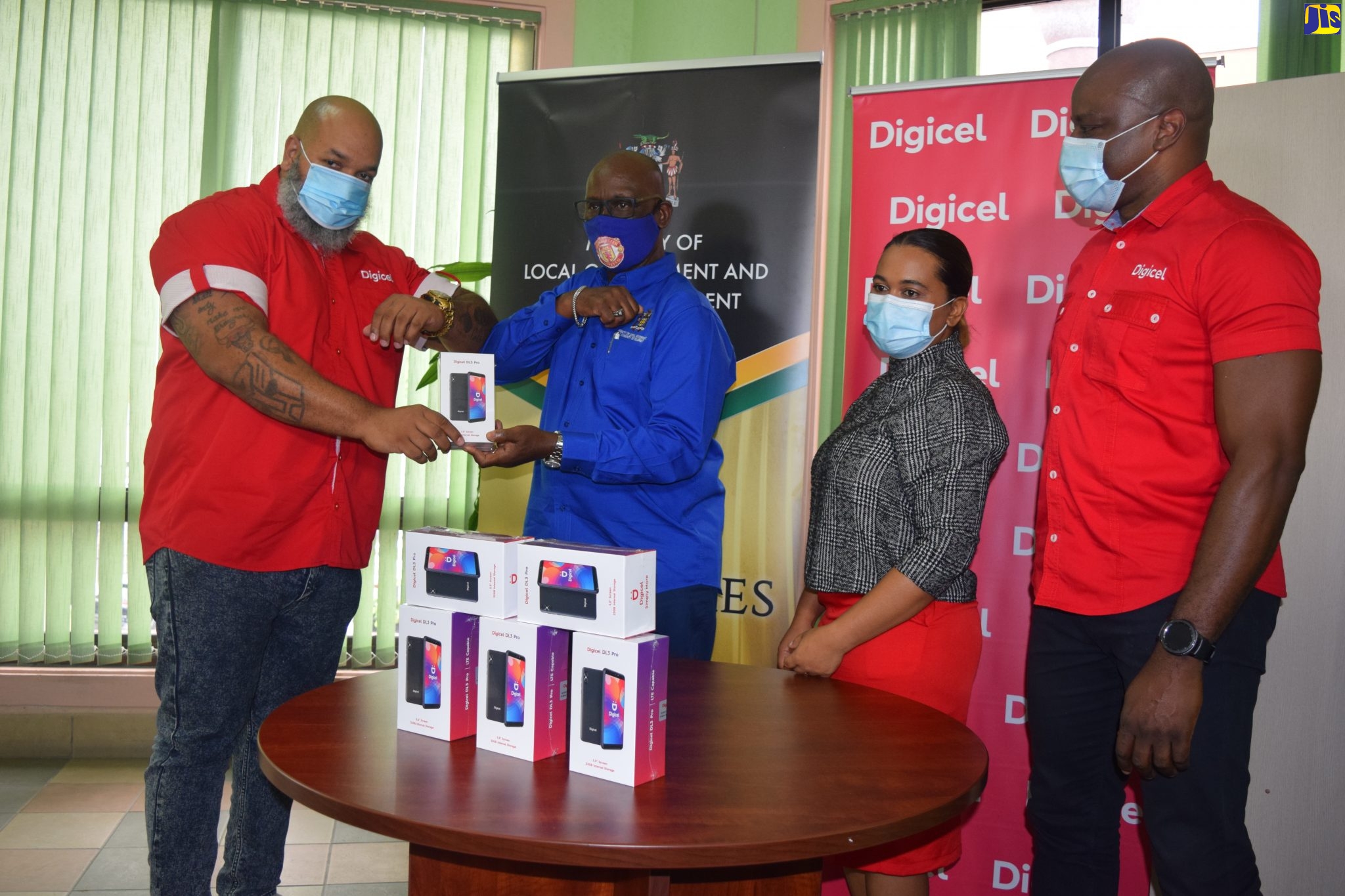 Minister of local Government and Rural Development, Hon. Desmond McKenzie (second left) receives a donation of smartphones from General Manager of Sales and Distribution at Digicel, Jeremy Owen (right), today (December 16),  at the Ministry, in Kingston.  The smartphones will be used to enhance the ‘Virtually Connected While Staying Socially Distant Initiative’, being implemented in Infirmaries and Golden Age Homes by the Ministry of Local Government and Rural Development. Sharing the moment are Treka Lewis, Secretary, Board of Supervision in the Ministry of Local Government and Rural Development and Public Relations and Communications Manager for Digicel, Elon Parkinson.