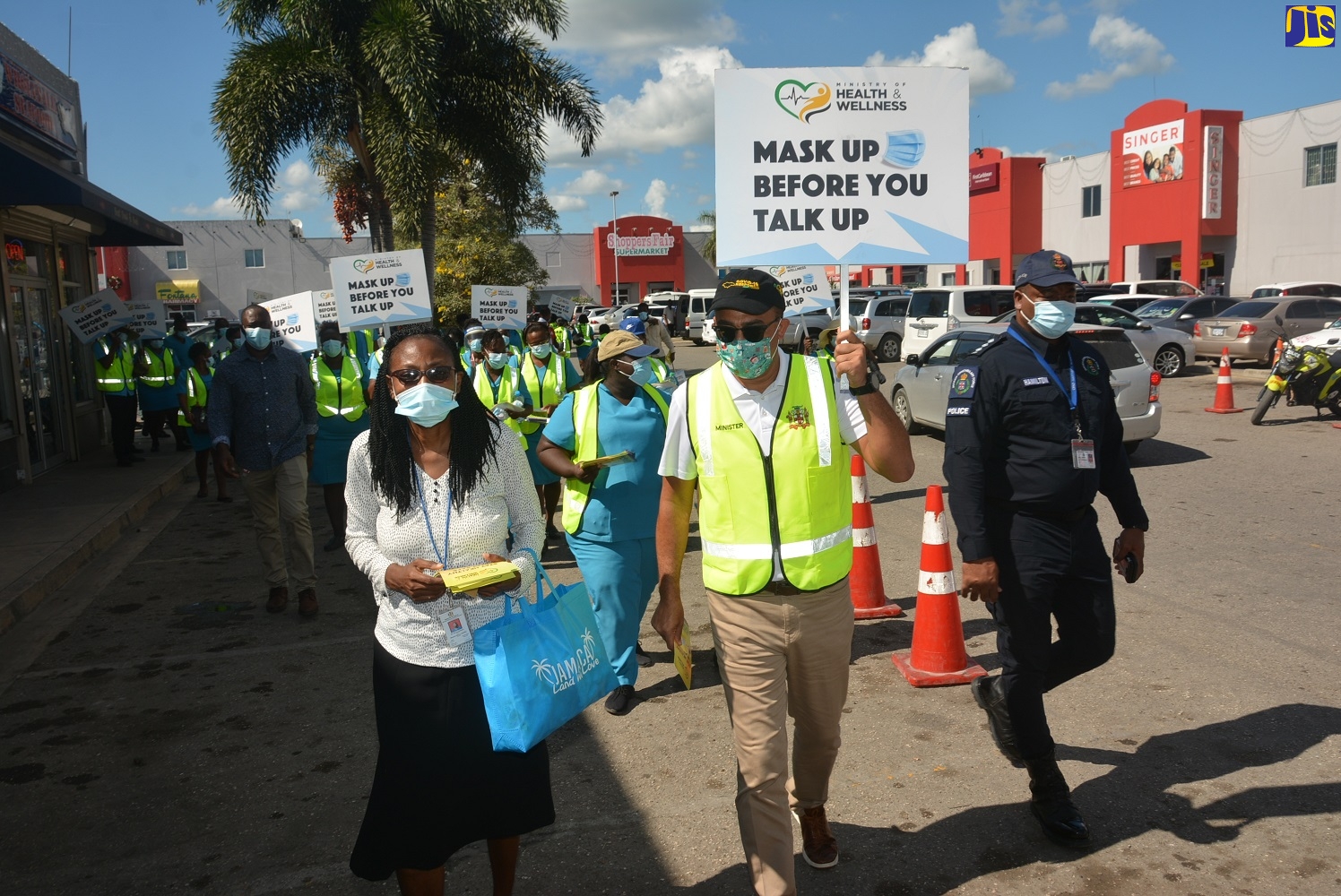 Minister of Health and Wellness, Dr. the Hon. Christopher Tufton (centre), and Medical Officer of Health for Westmoreland, Dr. Marcia Graham (left), lead a group of health workers during a road promotion of the ‘Mask Up Before You Talk Up’ COVID-19 campaign in the town of Savanna-la-Mar, Westmoreland, on Monday, December 14. At right is Deputy Superintendent of Police (DSP) in charge of Operations in Westmoreland, Adrian Hamilton.