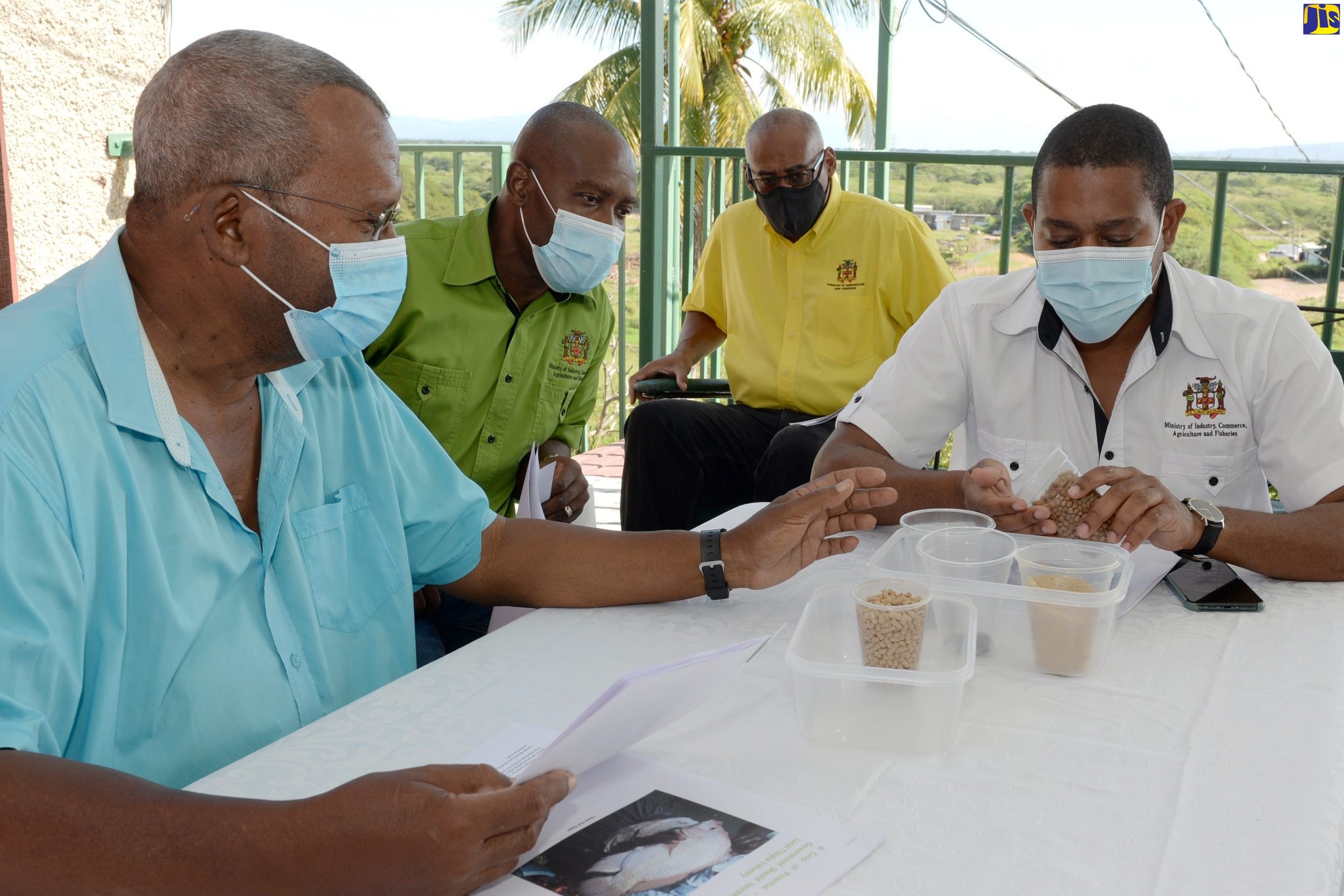 Minister of Agriculture and Fisheries, Hon. Floyd Green (right), has a close look at pellets used to grow freshwater fish, while on a tour of the Longville Park Farms in Clarendon on Monday (December 28). Owner of the facility, Donovan Bunting (left), highlights the features of the pellets, while Chief Executive Officer of the National Fisheries Authority, Courtney Cole (second left), and Chief Technical Director in the Ministry, Michael Pryce, look on.