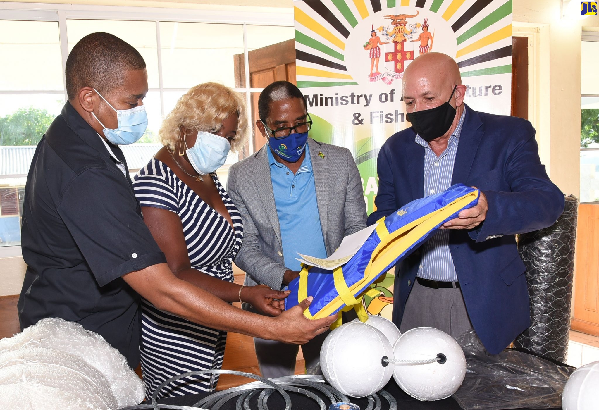 Minister of Agriculture and Fisheries, Hon. Floyd Green (left), looks at a life jacket, which was among fishing gear and equipment on display at a ceremony for the handover of grants to fishers from St. Mary at the St. Theresa Roman Catholic Church in Annotto Bay on Thursday (December 17). Others (from left) are President of the South East St. Mary Fisherman’s Group, Natalee Lynch; Minister of State for Industry, Investment and Commerce and Member of Parliament for St. Mary South Eastern, Norman Dunn; and Board Chairman, National Fisheries Authority, Leuitenant Commander George Overton.