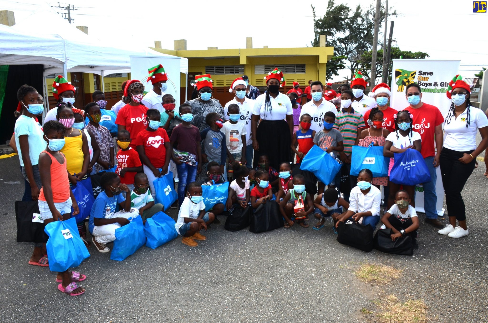 Wife of the Prime Minister, the Most Hon. Juliet  Holness (centre), along with personnel from Grocers of Jamaica, shares a moment with children from the Harbour View and Bull Bay communities in St. Andrew, who were presented with gifts and care packages on Wednesday (December 16) at St. Benedict’s Primary School in Harbour View.