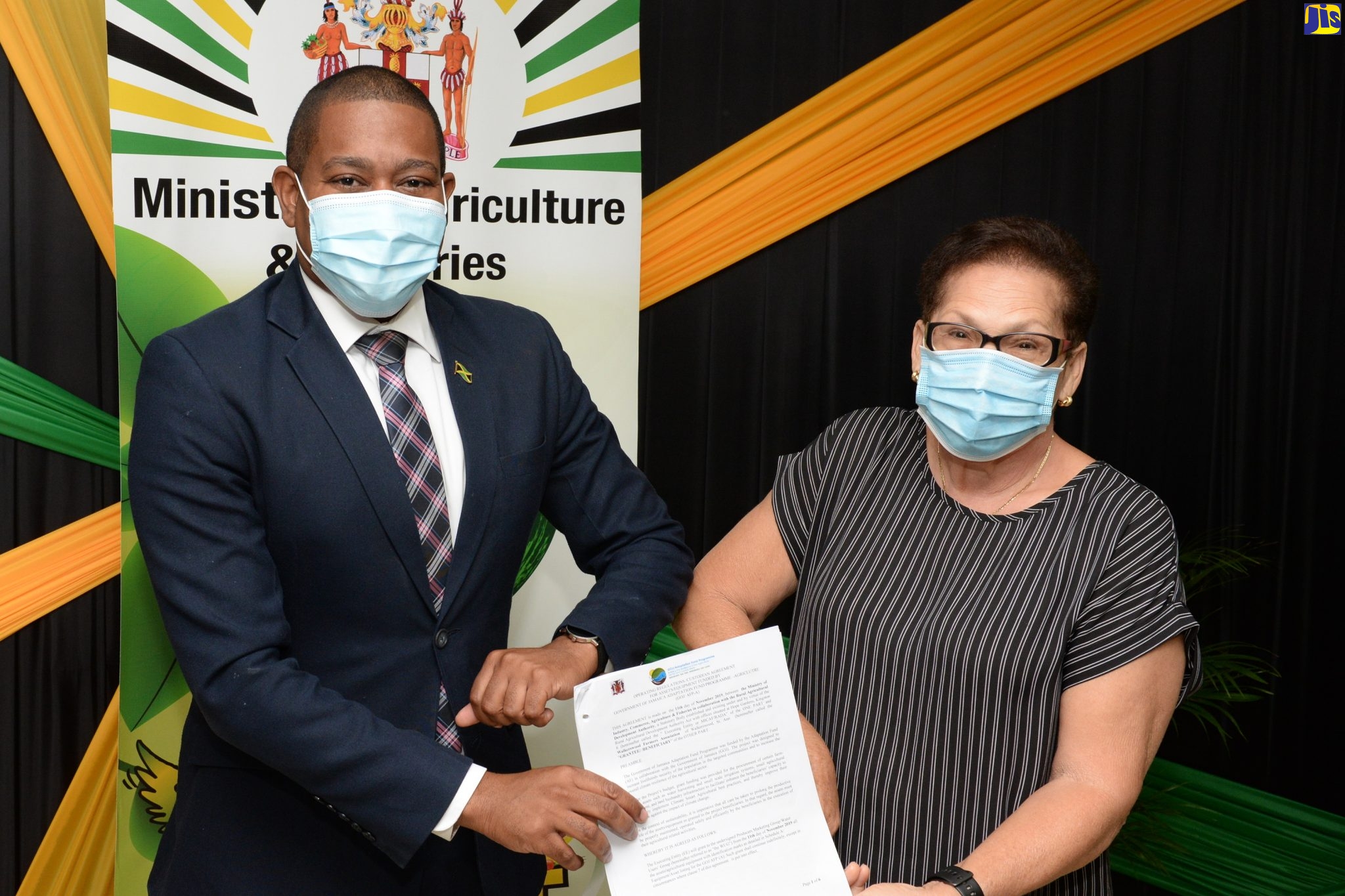 Minister of Agriculture and Fisheries, Hon. Floyd Green; and President of the Walkerswood Farmers’ Association, Denyse Perkins bumping elbows after signing the custodian agreement for the handover of water harvesting infrastructure to farming groups, during a ceremony at the  Ministry’s Hope Gardens location on December 16.