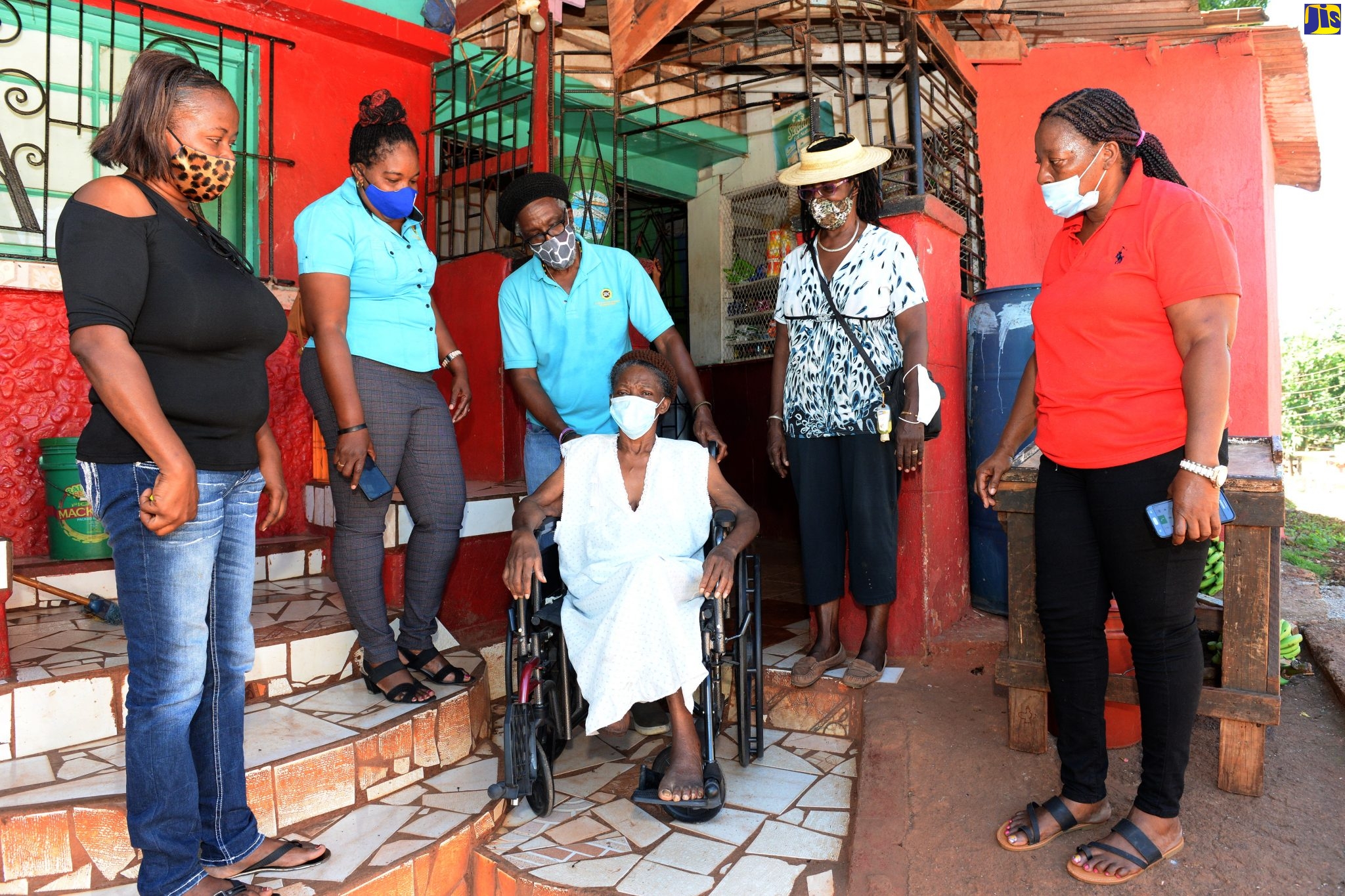 Community Development Officer with the Social Development Commission (SDC), Denzil Kerr (third left), assists Claudette Walters (in wheelchair), after presenting her with the unit, donated by Food For the Poor (FFP), at her home in Kitson Town, St. Catherine, on December 8. Sharing the moment (from left) are daughter of Miss Walters, Natoye Ferguson; SDC Field Supervisor, Janice Golding Williams; President of the Kitson Town Central Citizens Association, Carmen Barton, and executive member of the Association, Carole Morgan.