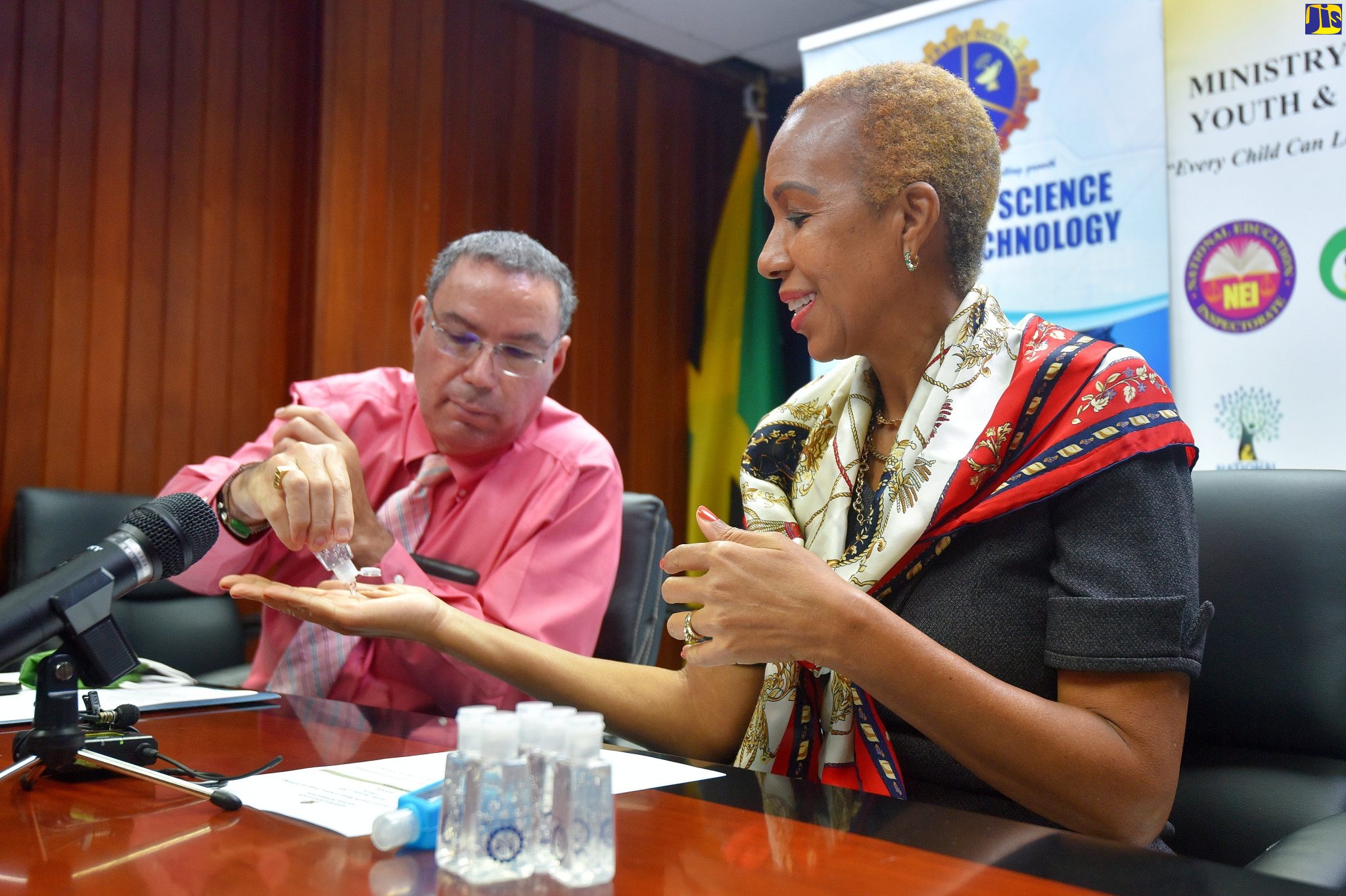 Minister of Science, Energy and Technology,  Hon. Daryl Vaz (left), shares a bottle of hand sanitiser with Minister of Education, Youth and Information,  Hon. Fayval Williams, during the handover ceremony for 5,000 bottles of hand sanitiser at the Education Ministry’s office in Kingston, on Tuesday (December 1).