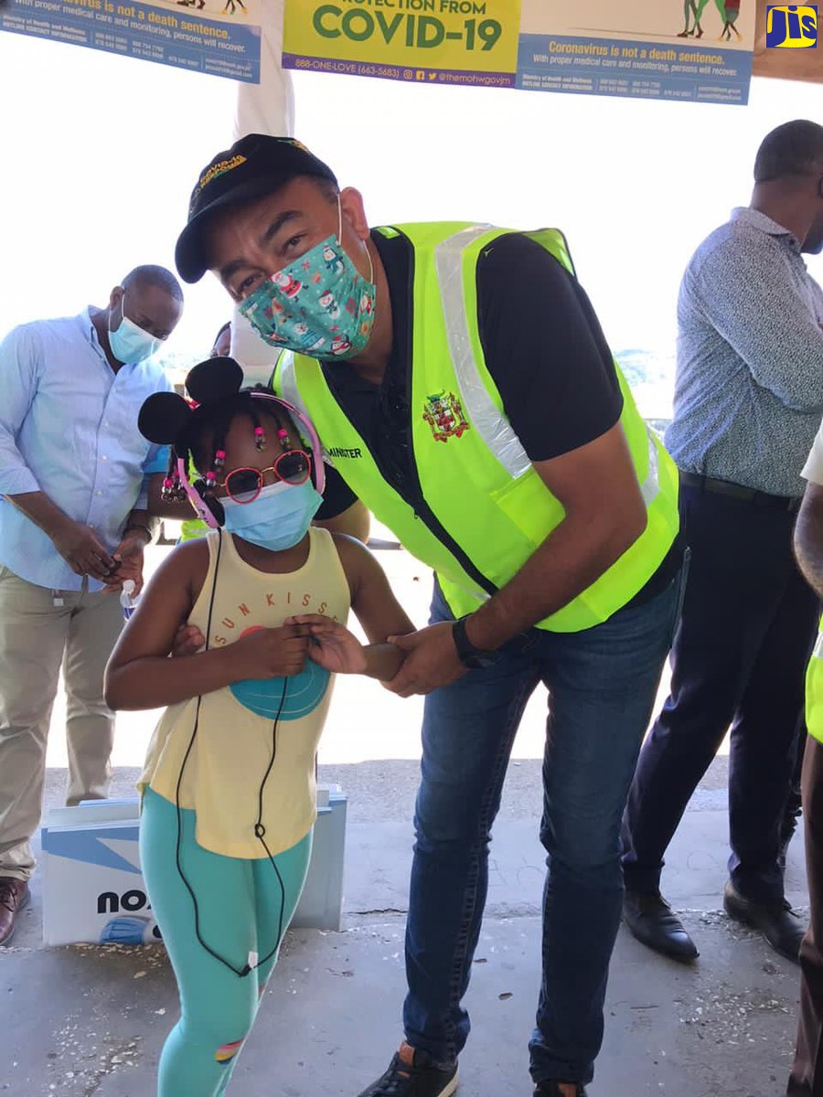 Minister of Health and Wellness, Dr. the Hon. Christopher Tufton, engages with a young Jhannah Chambers, during a tour of Lucea, Hanover, on December 15 as part of the ‘Mask Up Before You Talk Up’ coronavirus (COVID-19) awareness drive.