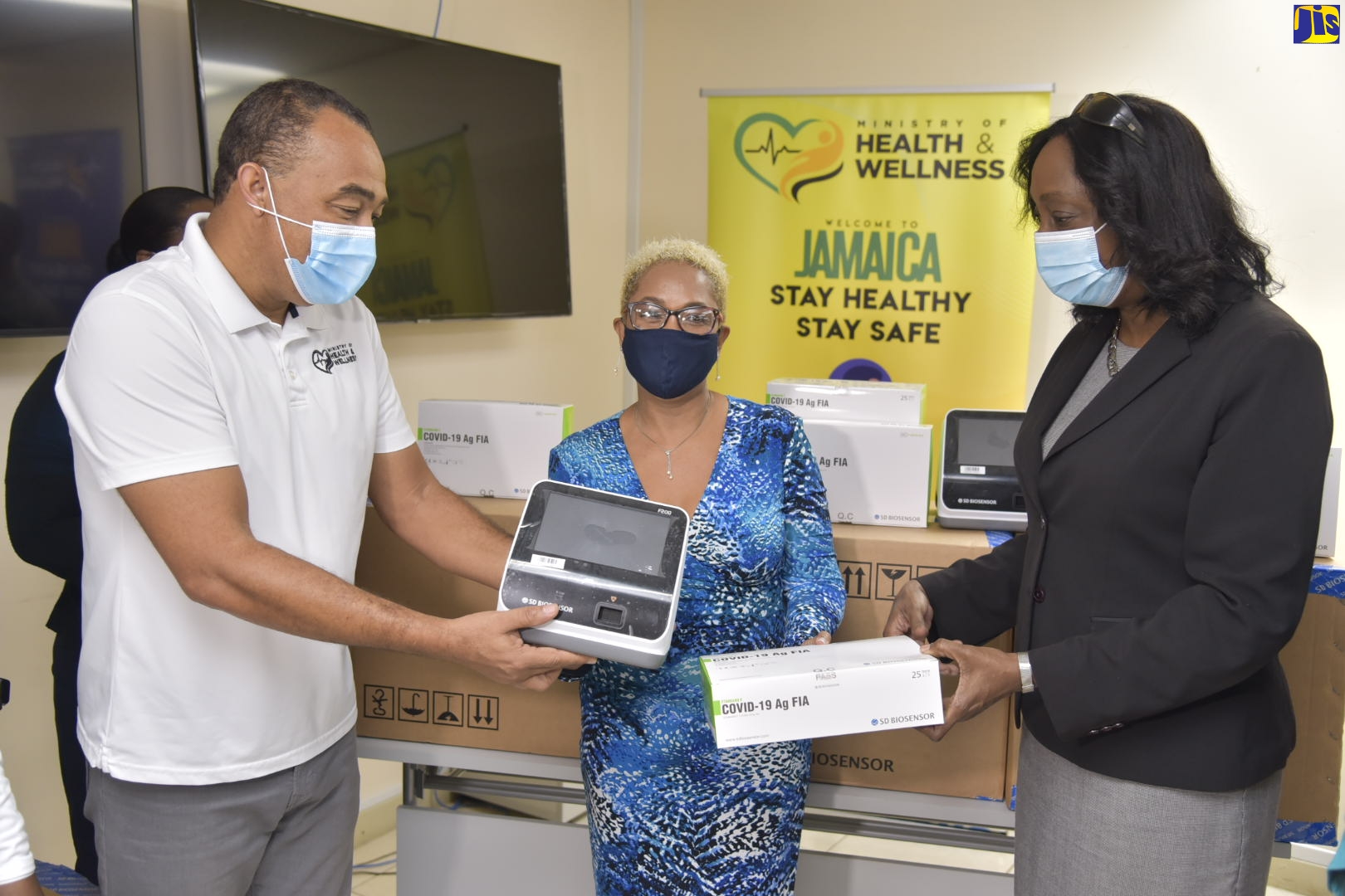 Health and Wellness Minister, Dr. the Hon Christopher Tufton (left), presents an antigen test reader to Chief Executive Officer (CEO), Biomedical Caledonia Medical Lab, Helen Christian (centre), at the Ministry’s New Kingston offices, on Thursday (January 14). Director of Laboratory Services in the Ministry, Dr. Michelle Hamilton, also presents the CEO with an antigen test reader. Occasion was the handover of 30,000 antigen test kits and reader machines to six private laboratories.