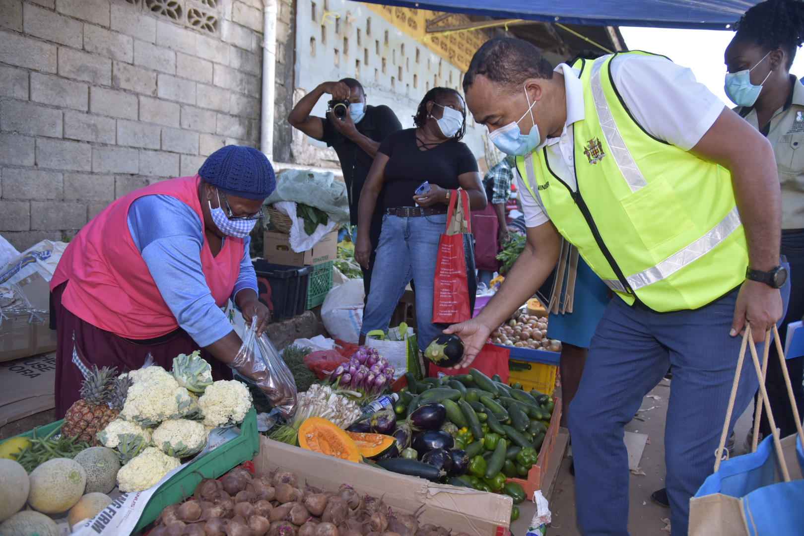 Health and Wellness Minister, Dr. the Hon. Christopher Tufton (right), purchases items from Miss June (left),  a vendor at the Mandeville Market, in Manchester, on January 27, during his ‘Market Pop-Up’. The Ministry has embarked on a campaign to encourage Jamaicans to eat fresh produce in order to boost their immune system to fight COVID-19.